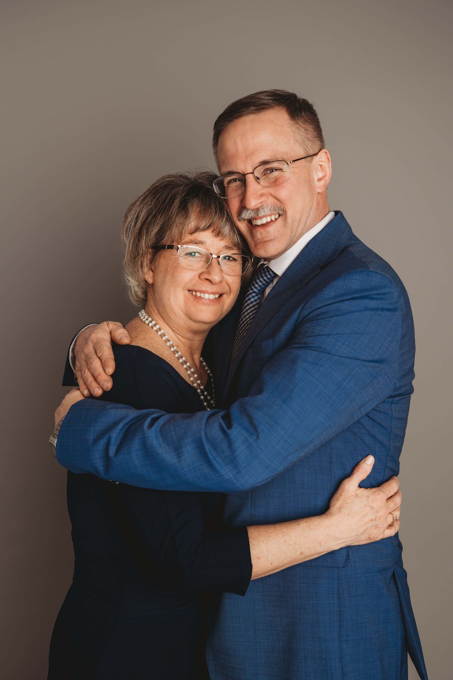 Elegant studio portrait of a couple hugging and smiling, captured by a Walla Walla studio photographer on a warm neutral background.