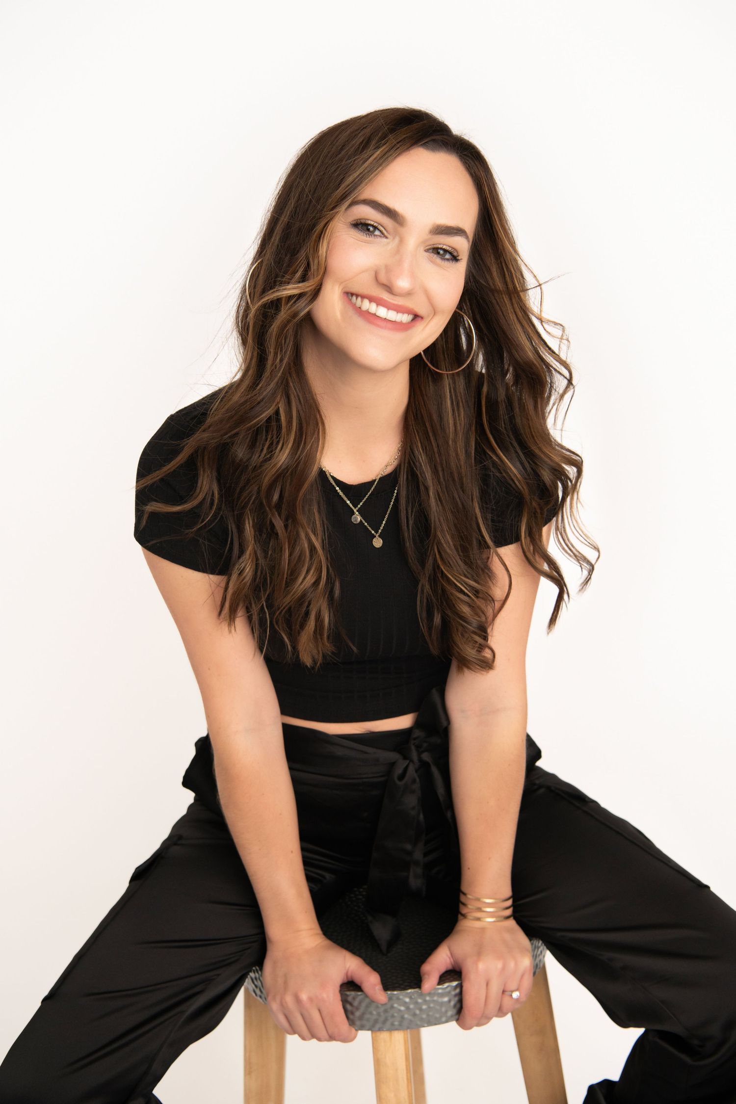 A woman seated on a stool smiling confidently for a headshot designed for personal and professional use.