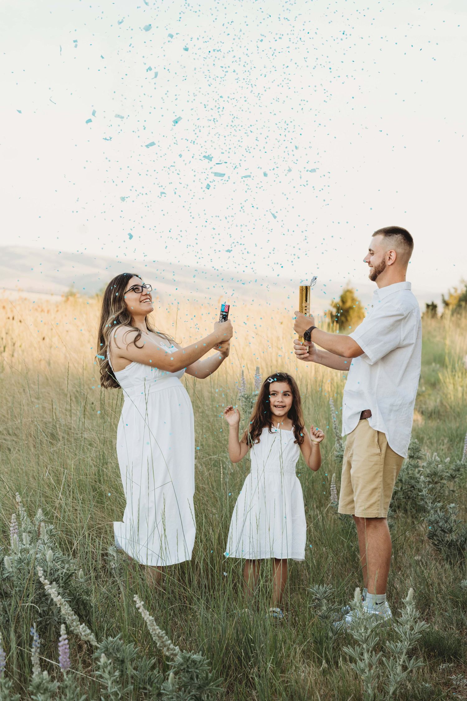 A family announcing the gender of their baby using blue confetti in a portrait taken by a Walla Walla maternity photographer.