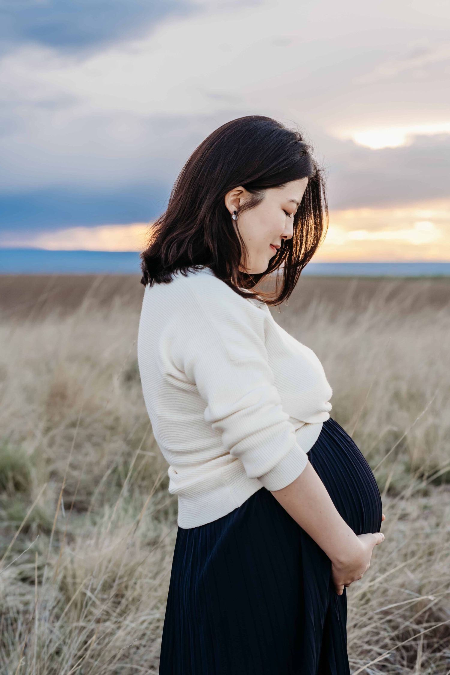 Side profile maternity portrait of a pregnant woman holding her baby bump during a sunset maternity session in Walla Walla.