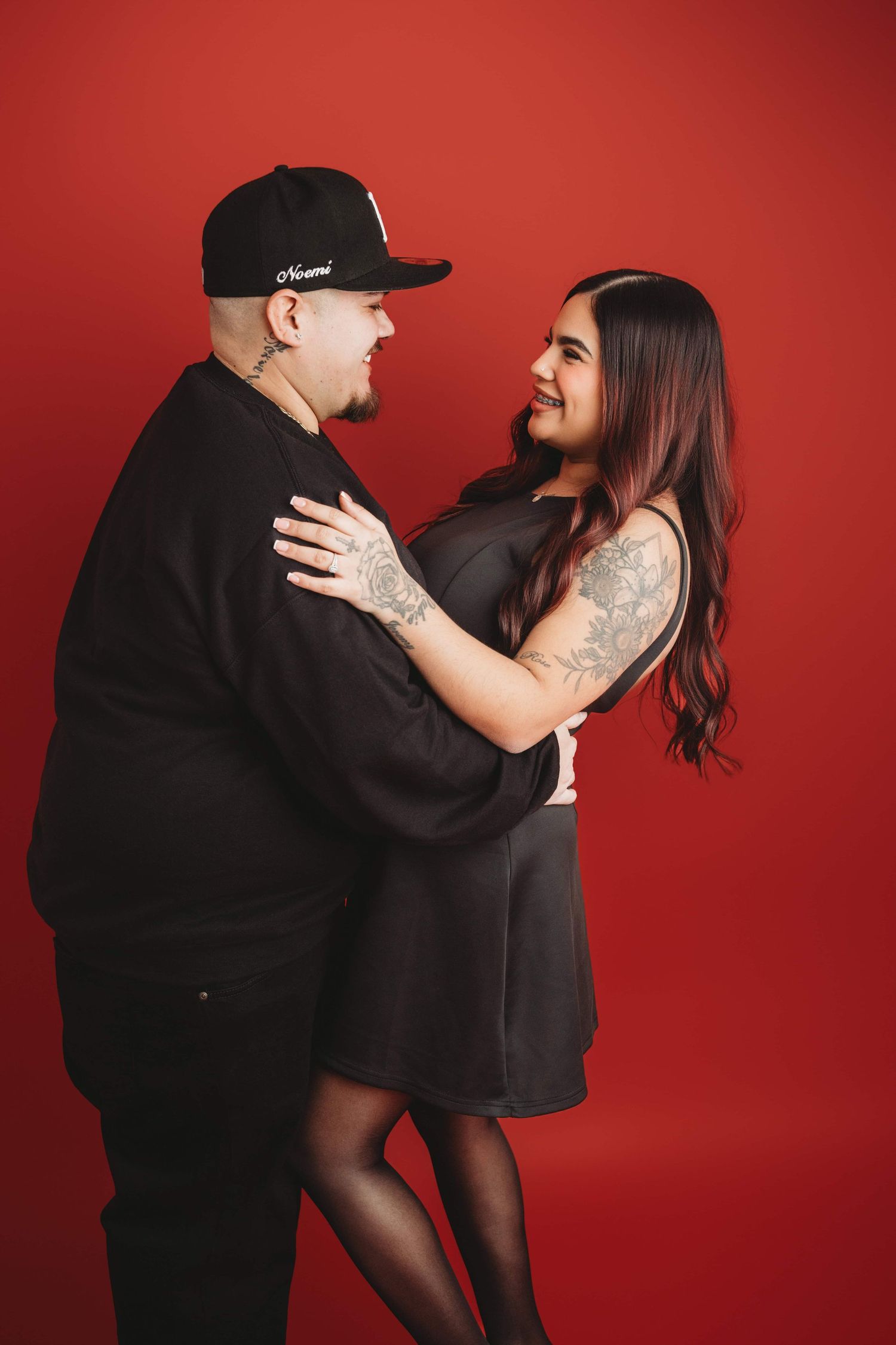 A couple looking at each other smiling on a red background at a studio in Walla Walla.