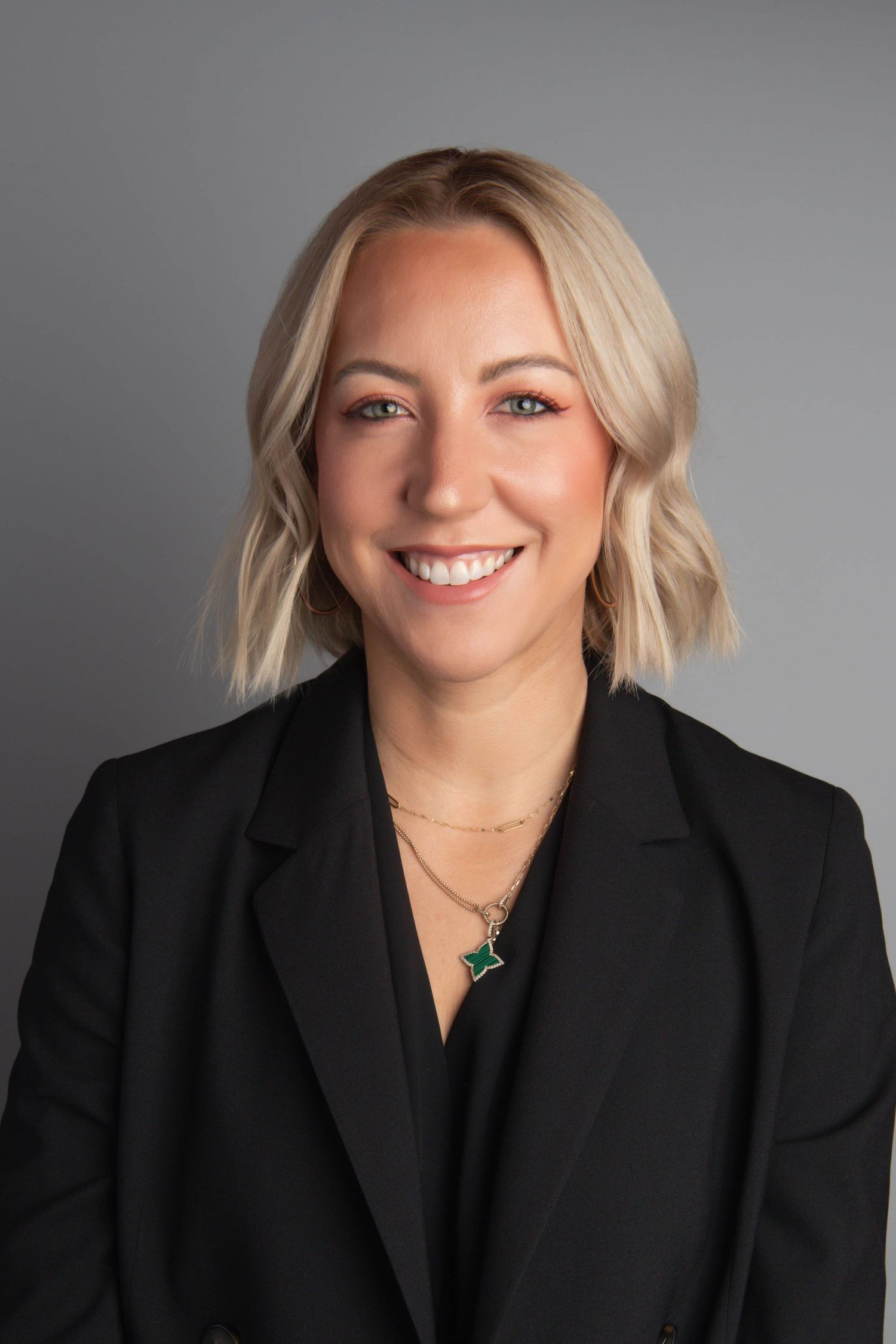 Studio headshot of a professional woman wearing a blazer and soft makeup