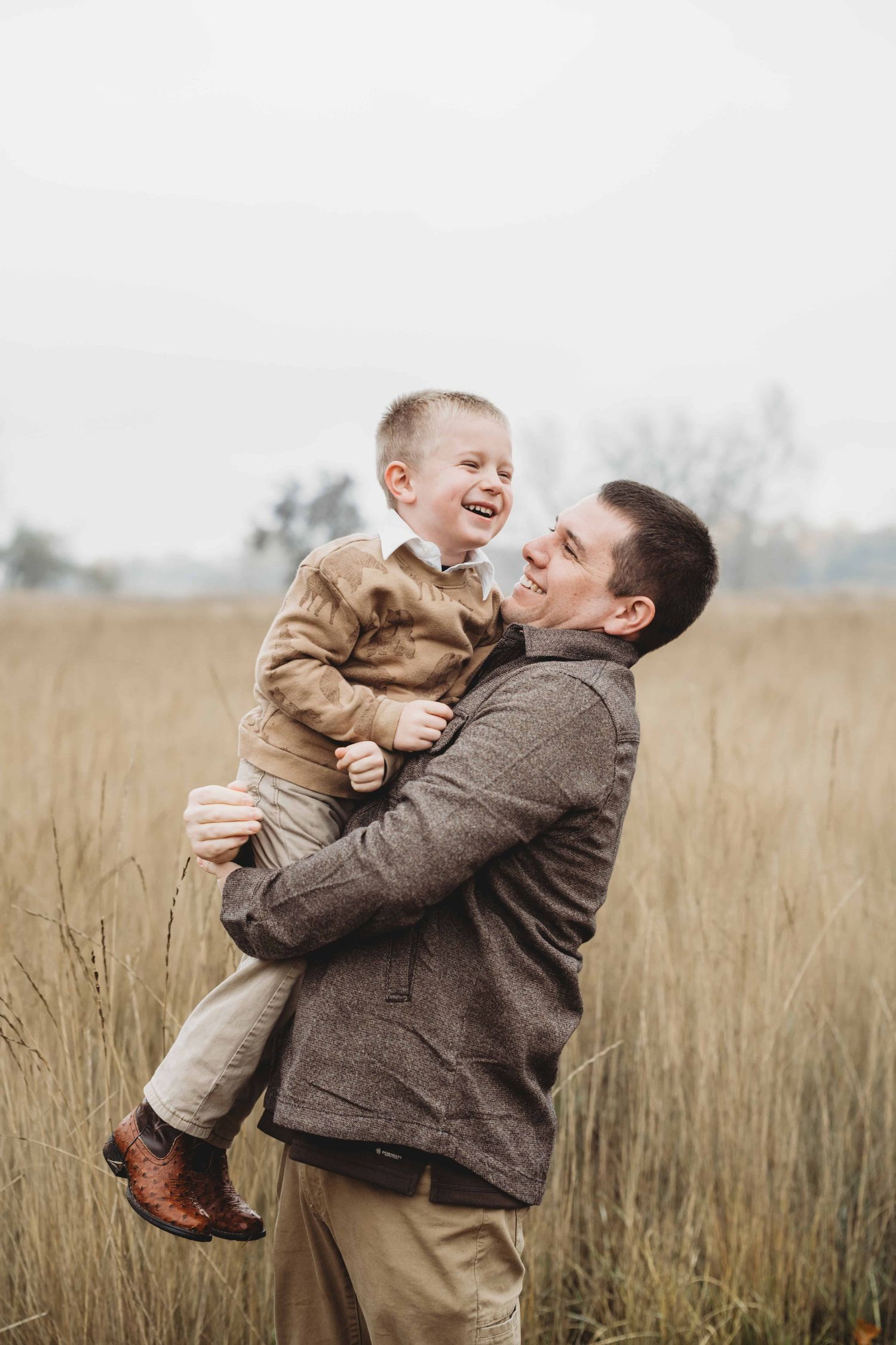 A dad holding his son and spinning him around in a candid family portrait, taken by a Walla Walla photographer.