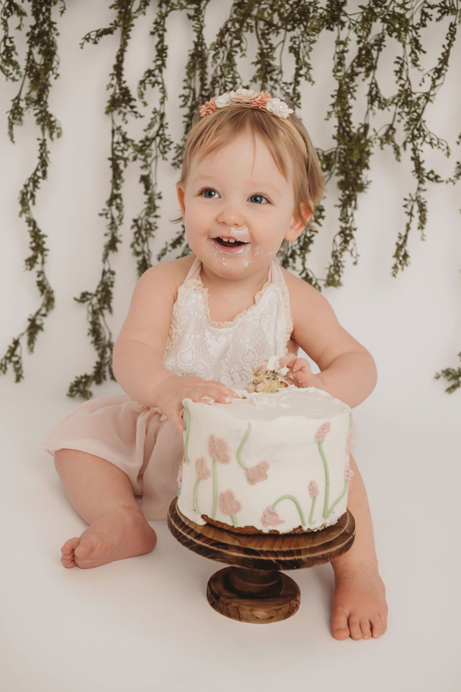 A one year old girl smashing her cake during her cake smash photoshoot in a Walla Walla studio.