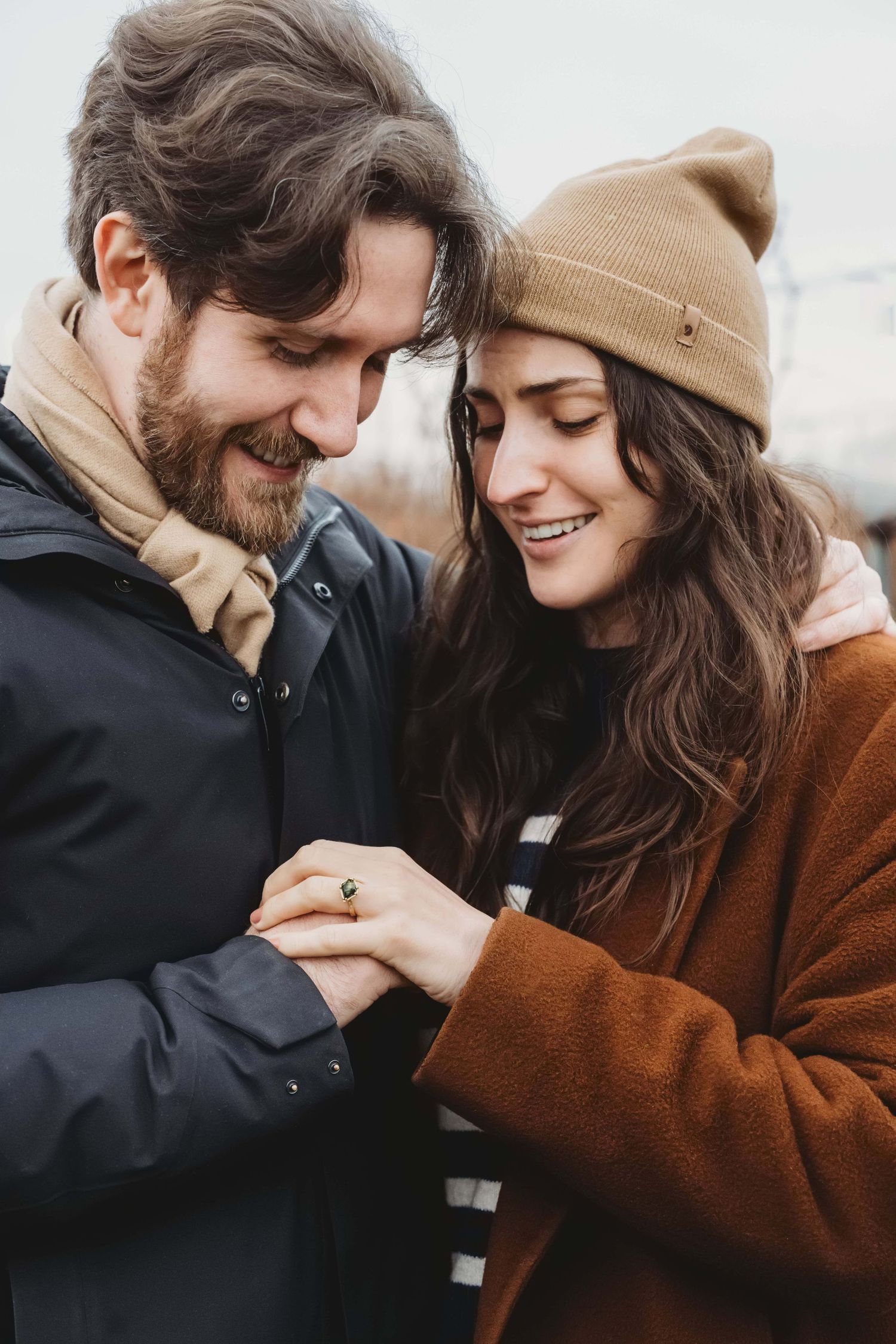 A couple sweetly looking at the ring that he just proposed with on her finger.