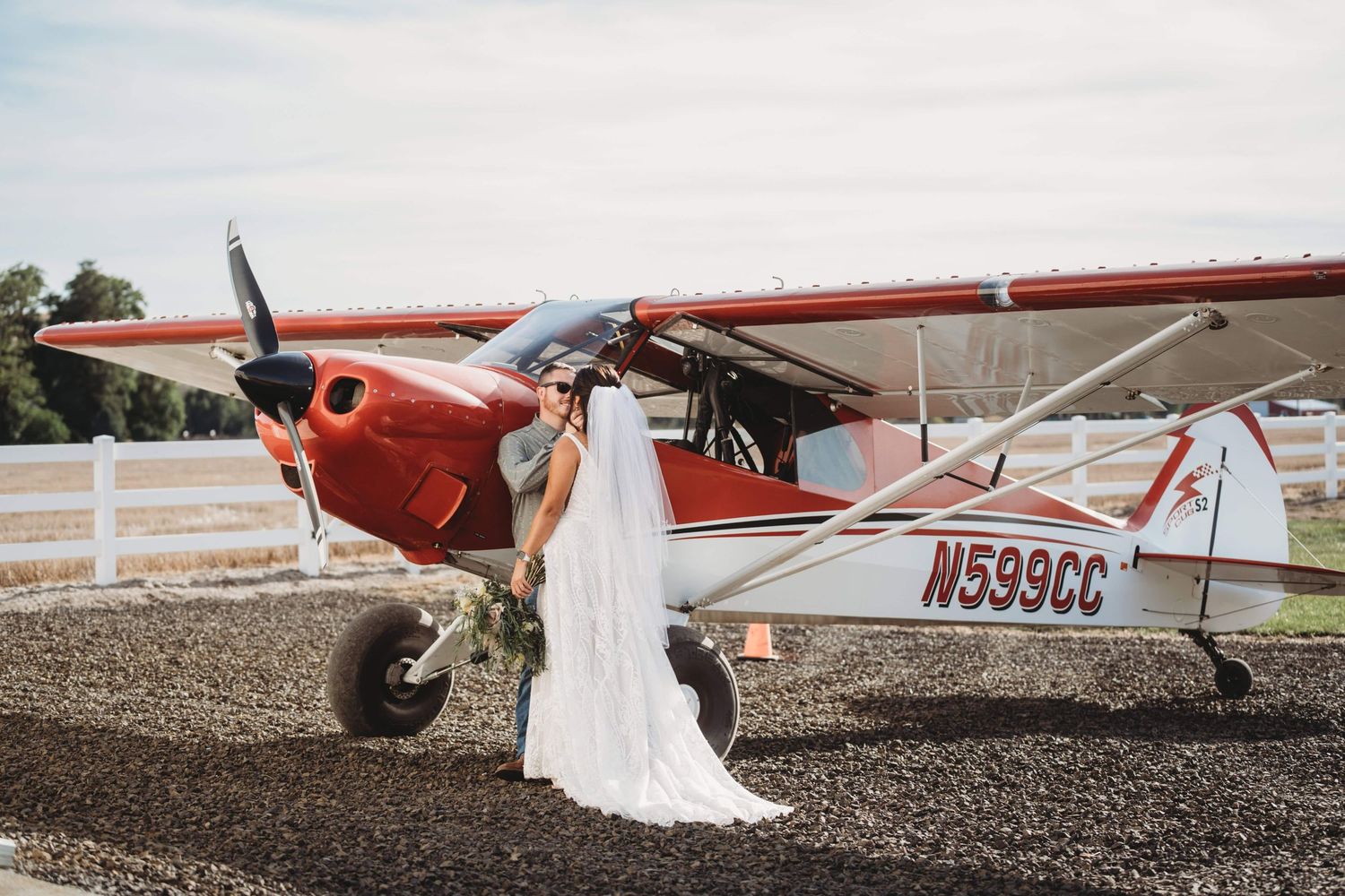 A couple leaning against a plane and kissing after their wedding