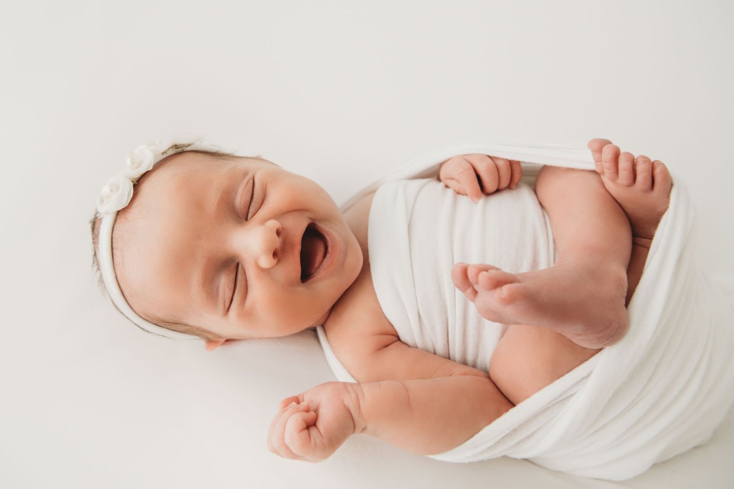 Newborn baby girl in a white newborn wrap photographed for a Richland Washington family