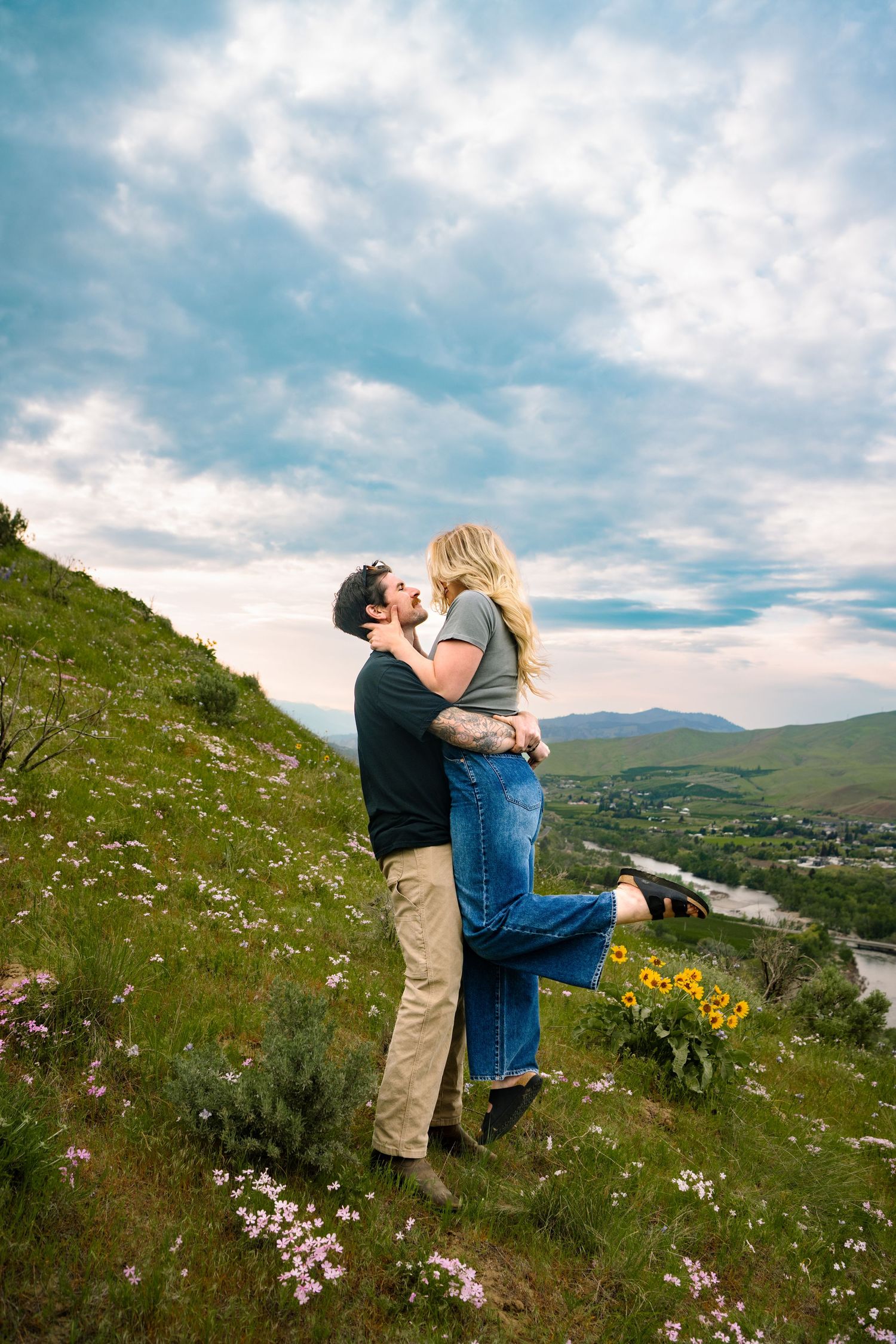 A man picking up his wife in a wildflower field in Wenatchee Washington.