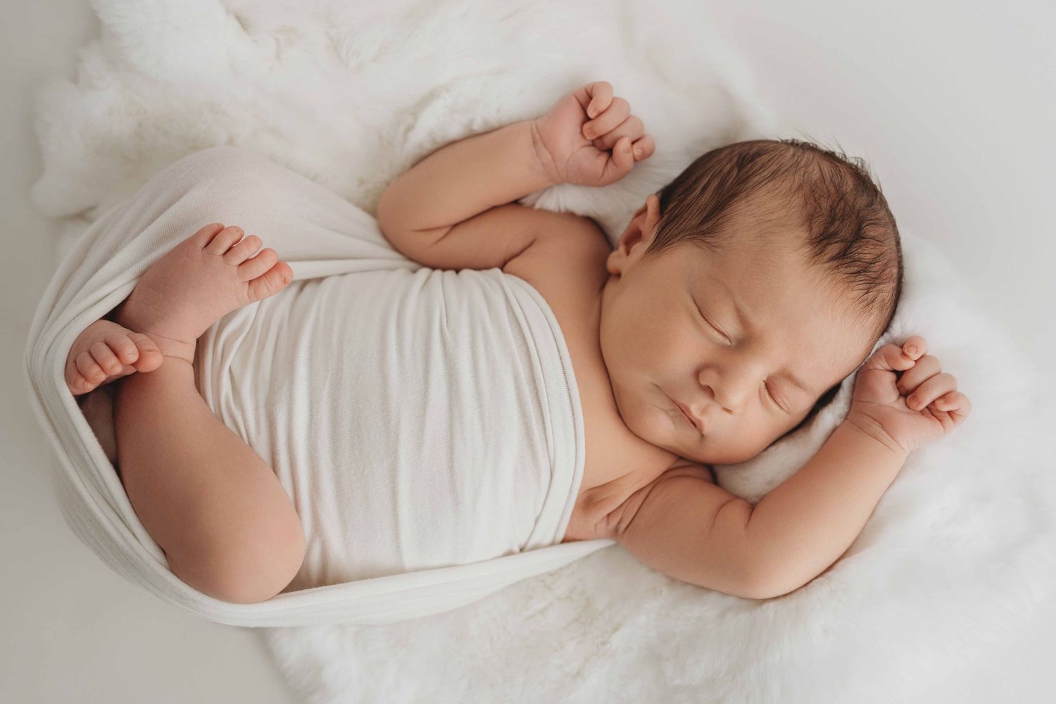 A chubby 10 pound newborn sleeping on a white backdrop at a Tri-Cities newborn photography studio.