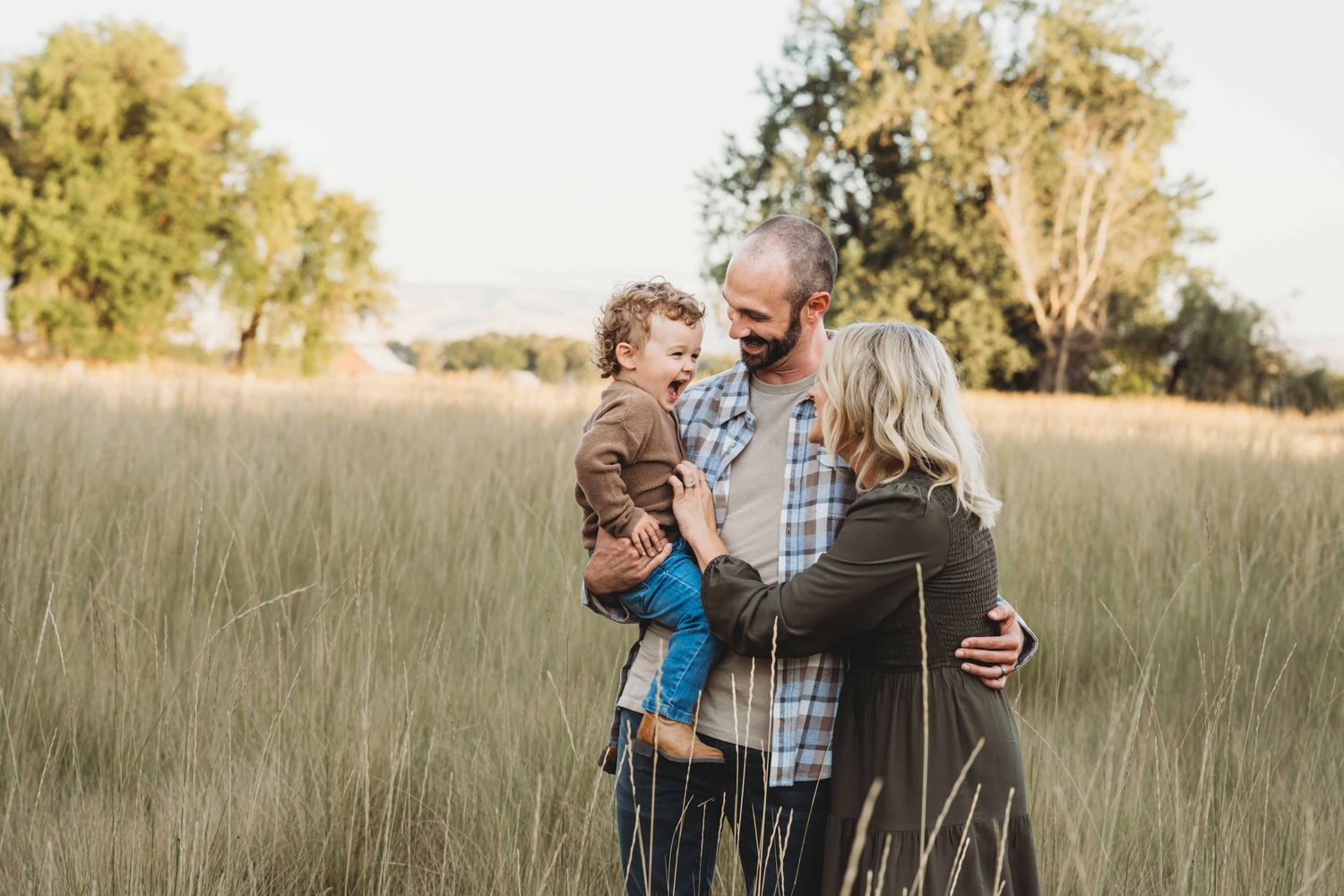Parents and their toddler playing with each other in a field.