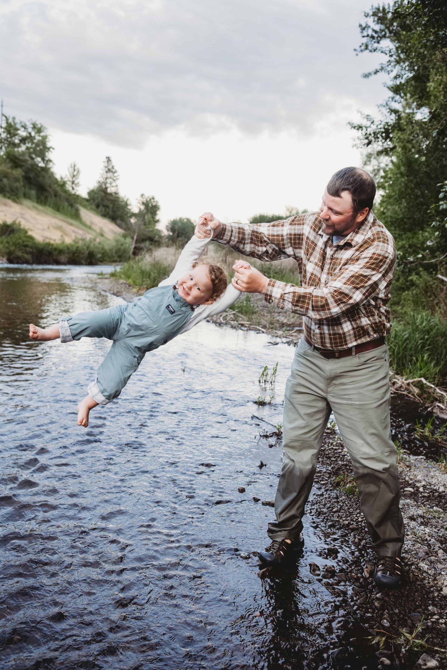A father swinging his toddler over a creek in Walla Walla.