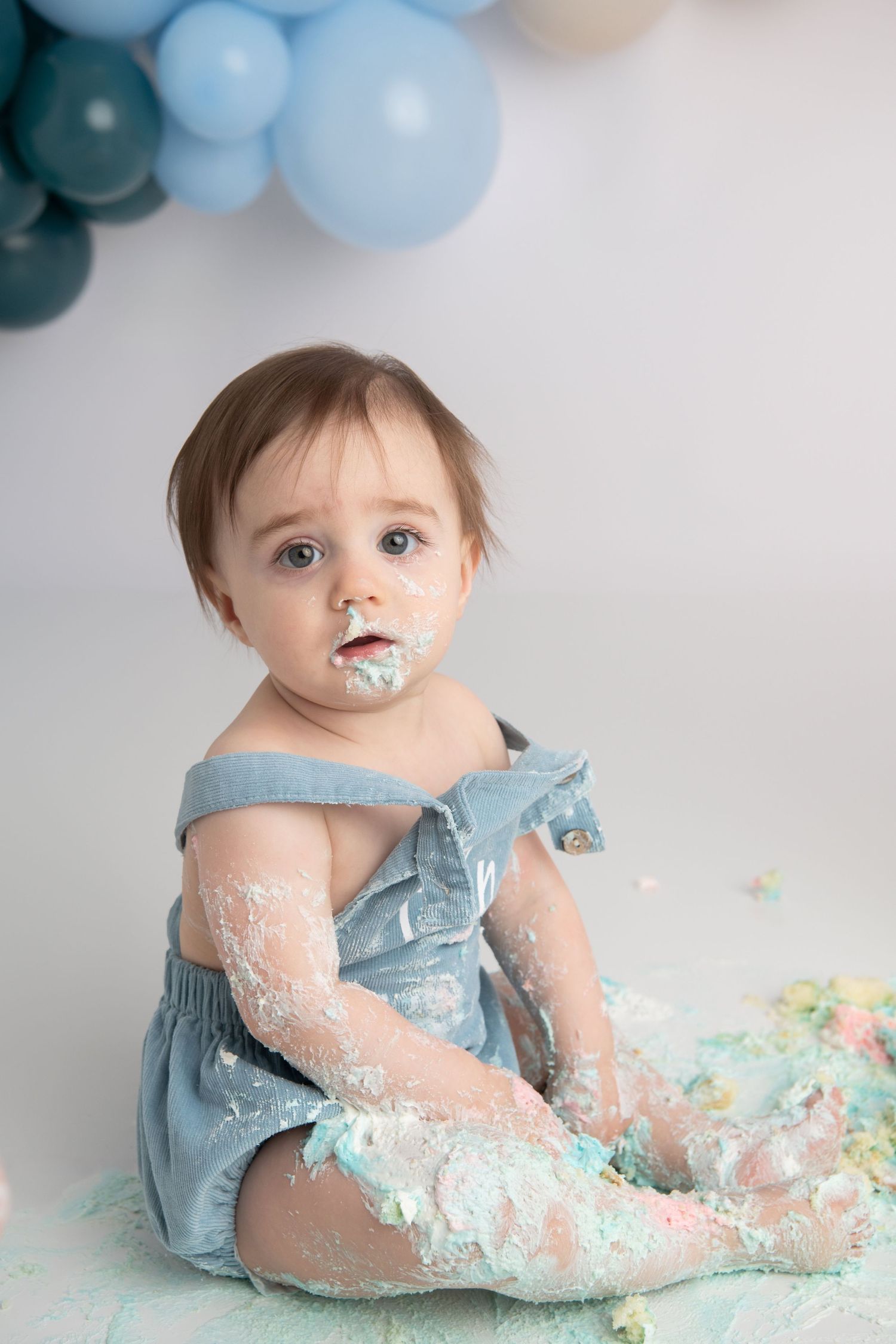 A one year old is covered in blue frosting after his cake smash photoshoot in Walla Walla.