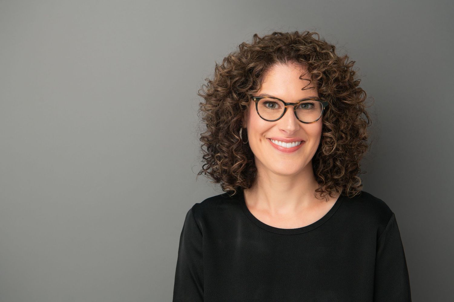 A woman wearing glasses and smiling confidently for a professional headshot in Walla Walla.