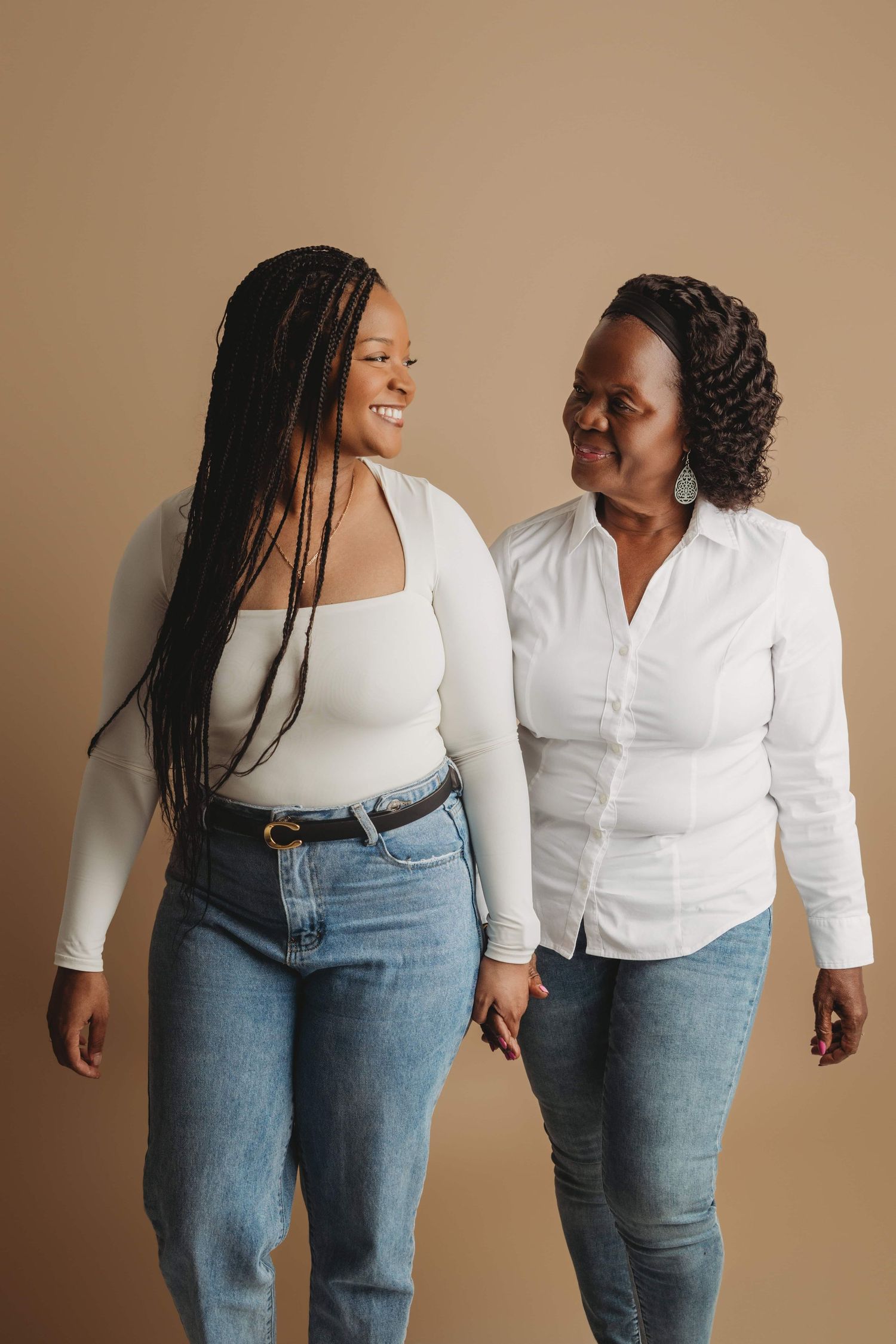 Two women standing holding hands in a studio on a brown backdrop in Walla Walla.
