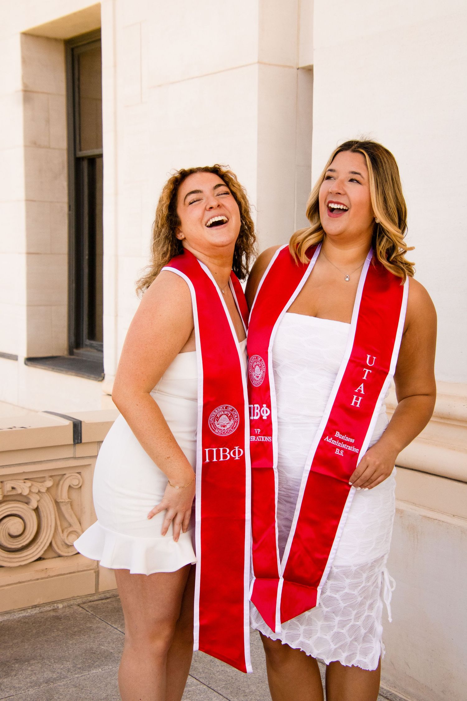 Two graduates in Pi Beta Phi stoles laugh together during photo session.
