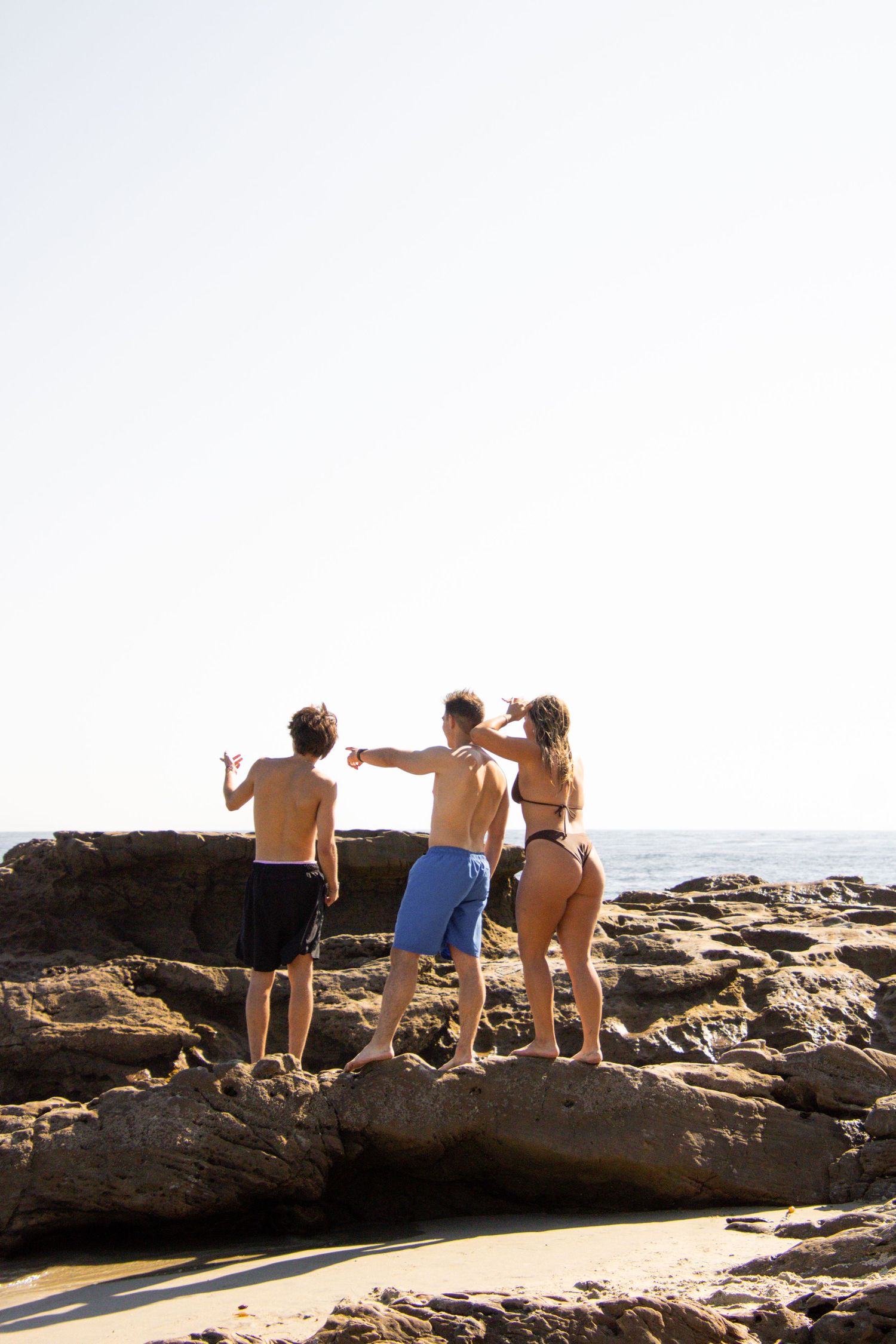 A group gathers on rocky coastal outcrops overlooking the ocean.