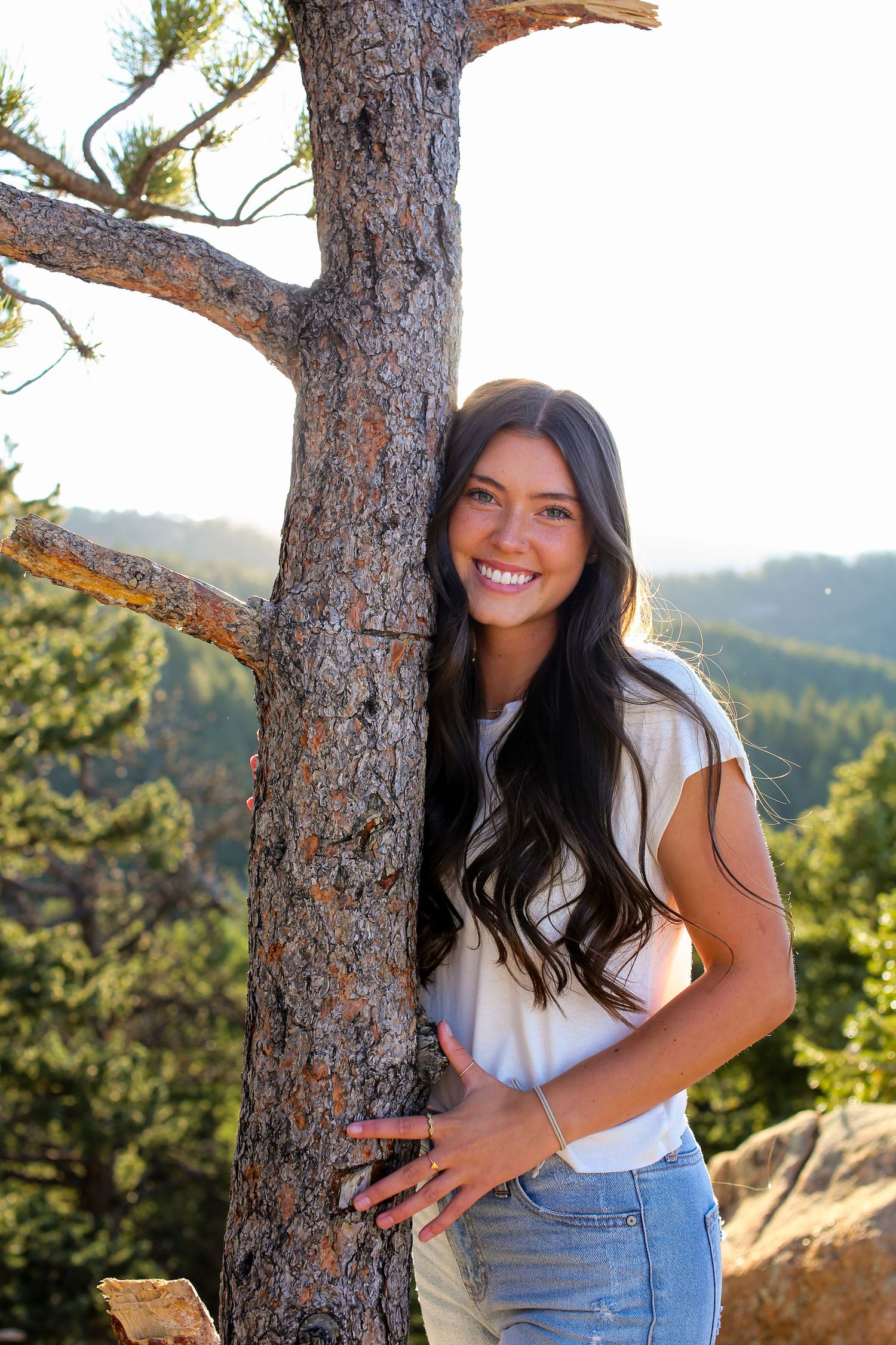 Outdoor portrait session against pine trees in mountain setting.