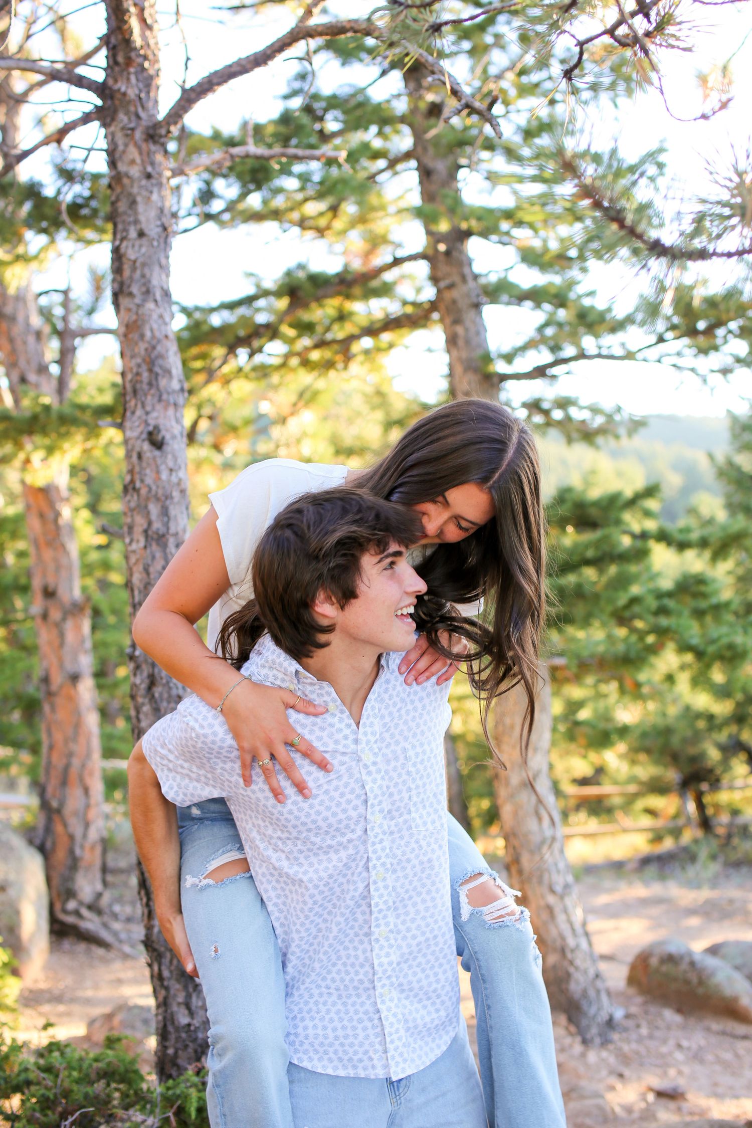 Couple sharing intimate moment in forest setting during golden hour.
