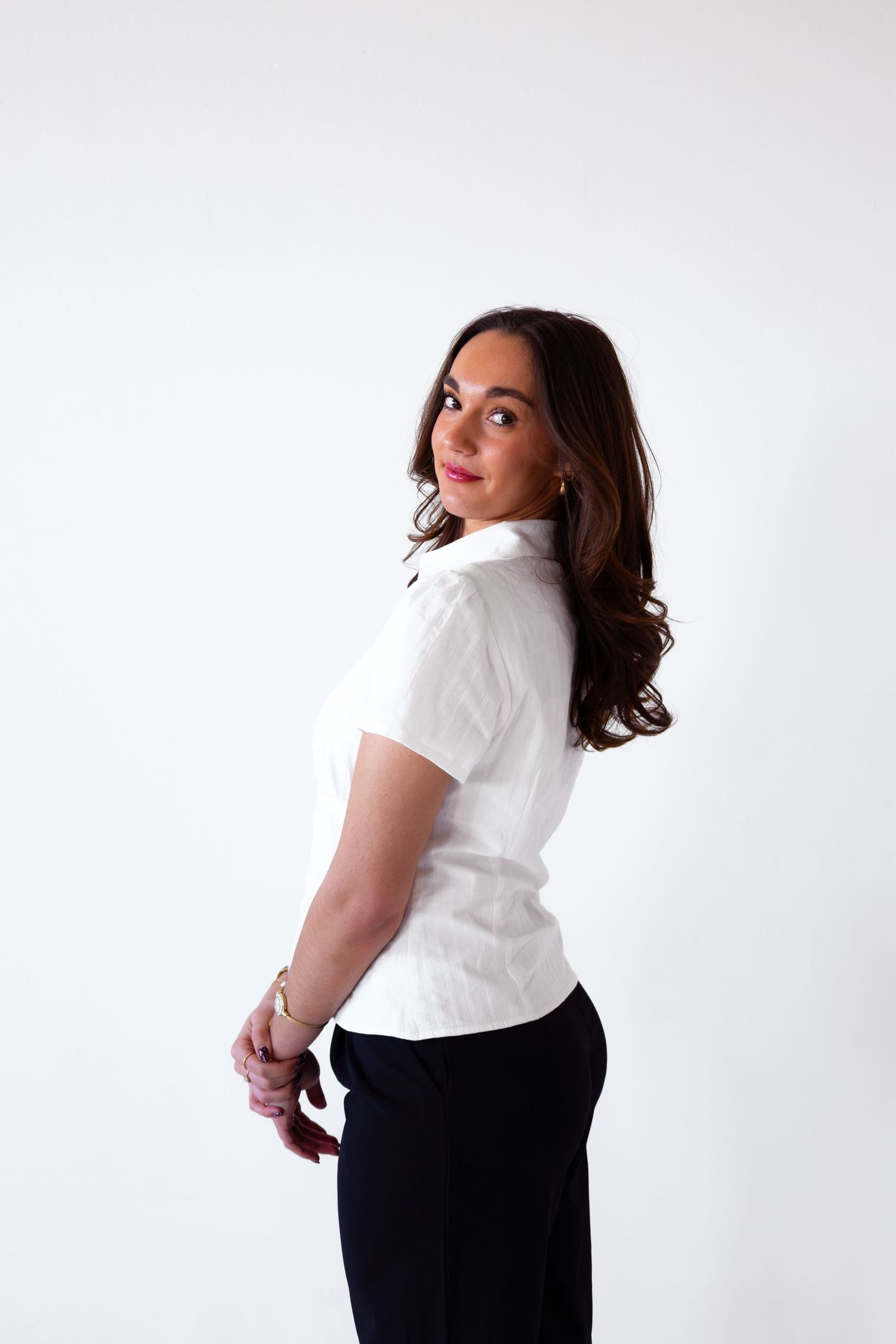 Fashion poses in white t-shirt and black pants against minimalist white studio background.