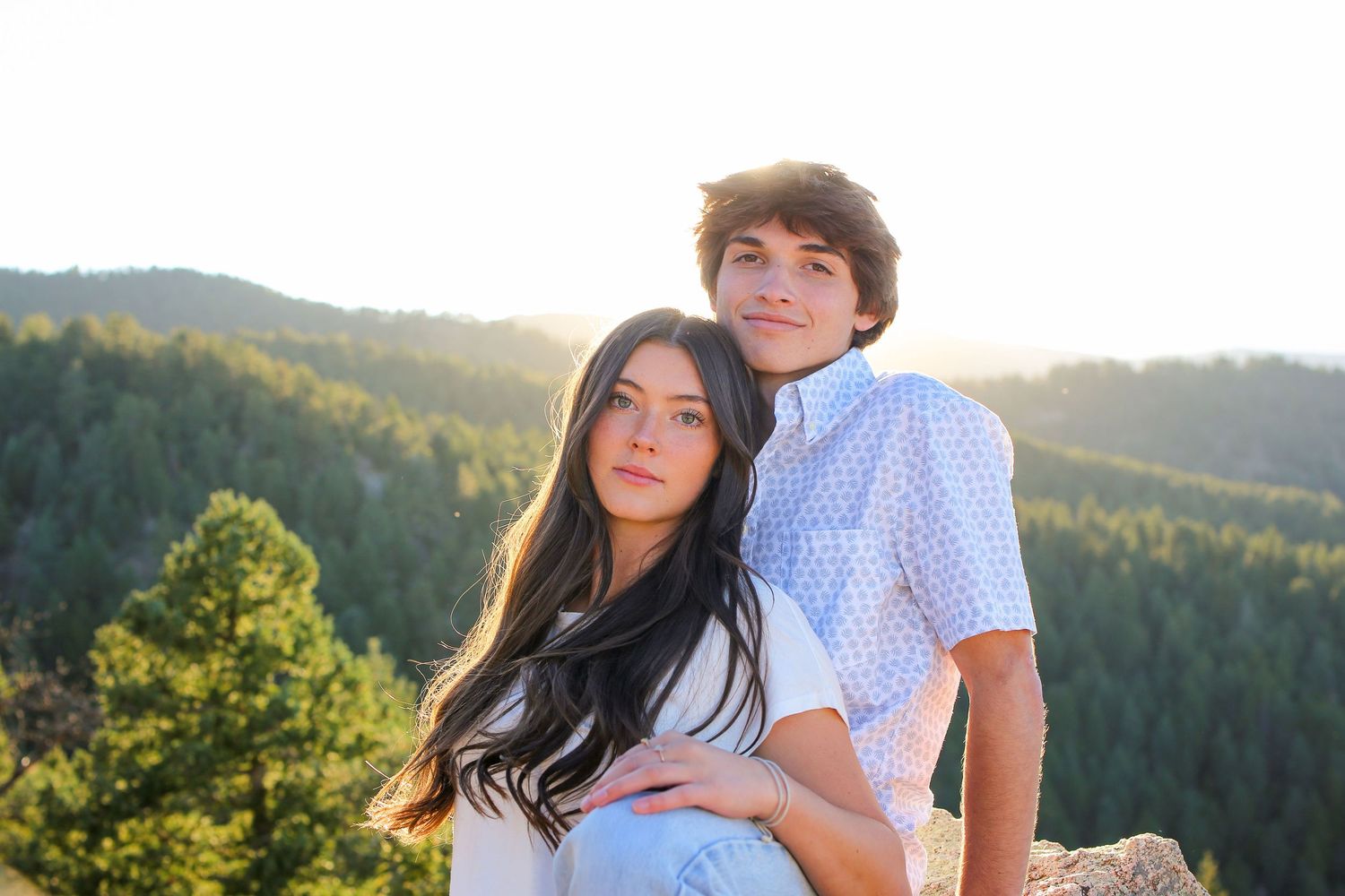 Happy couple in coordinated outfits sharing tender moment in mountain setting.