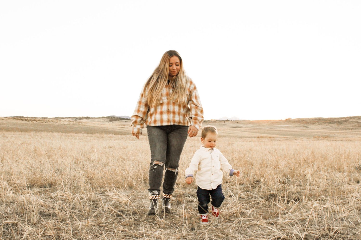 Family walking together through golden field at sunset.