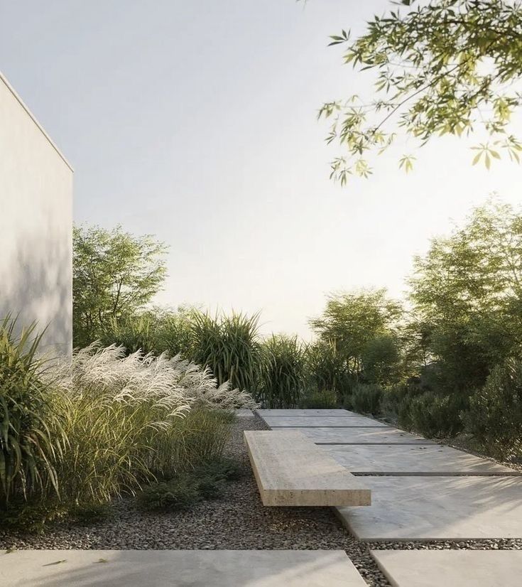 A modern concrete bench sits along a minimalist garden path with native plants and gravel landscaping.