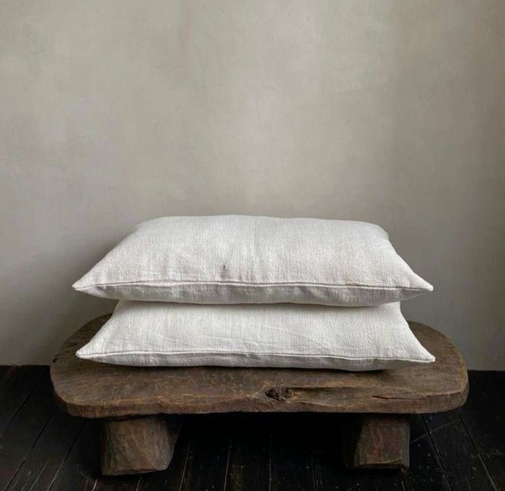 White linen pillow resting on rustic wooden bench against neutral wall. Kangaroo Island Haus Home KI Cleaning Maintenance interior design