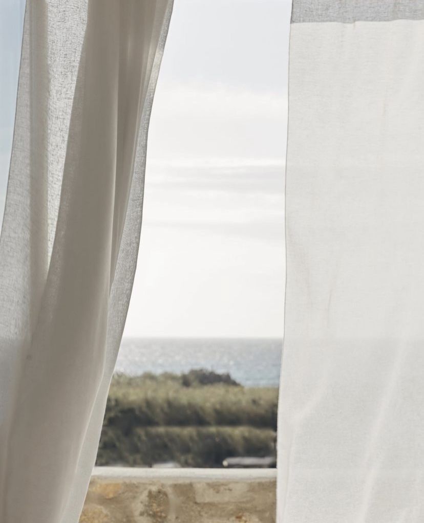 White curtains billow in front of a window overlooking a natural landscape with fields and trees in the distance. Kangaroo Island Haus Home