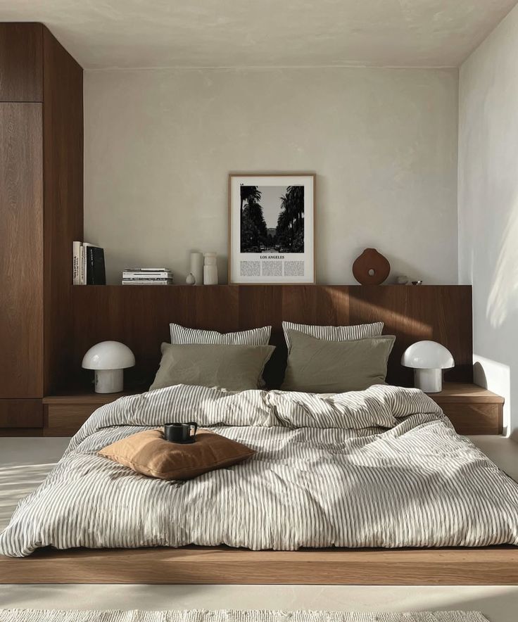 Modern minimalist bedroom with white bedding, wooden paneling, and mushroom table lamps on built-in nightstands.