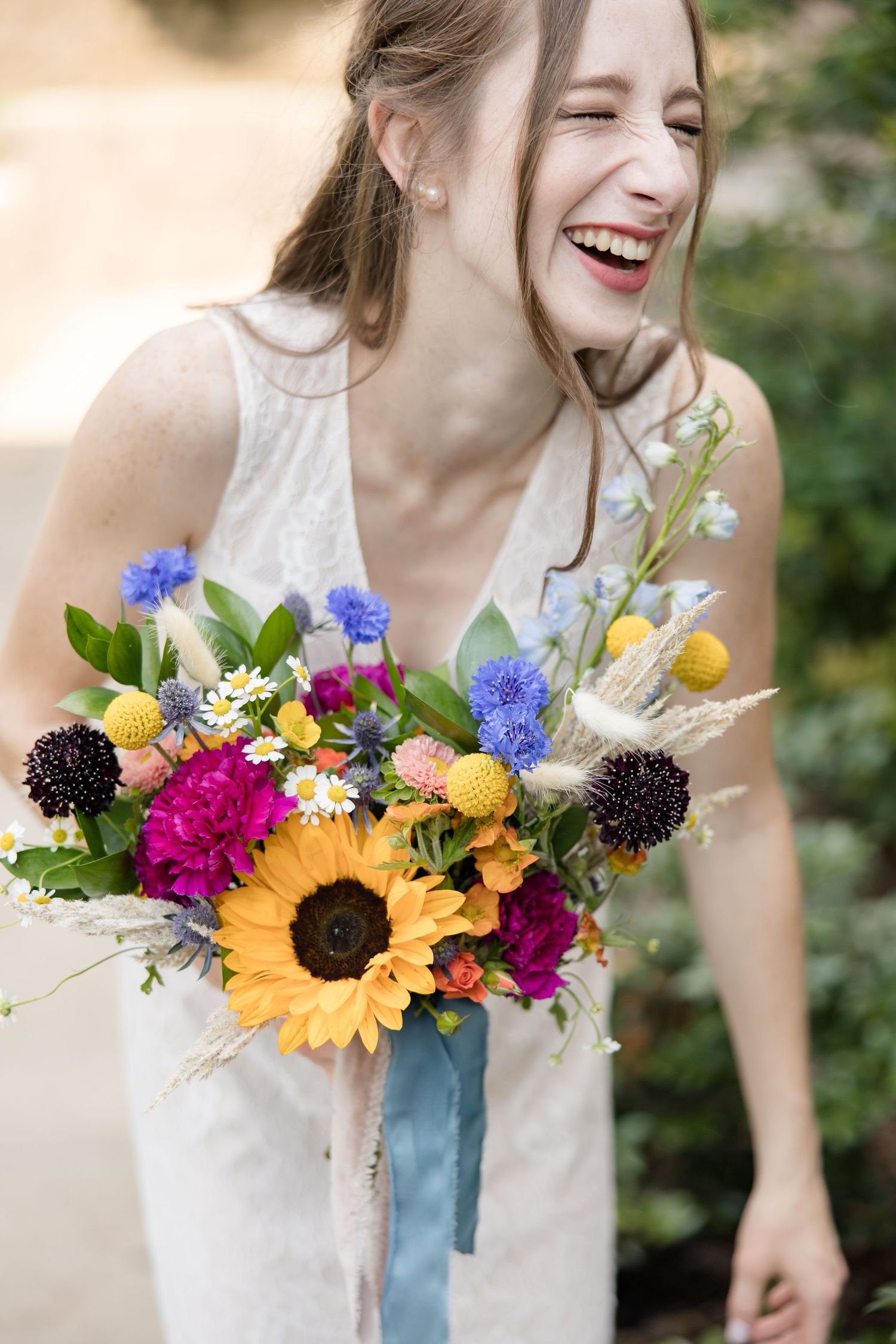 A joyful bride laughs heartily as she holds her brightly colored bouquet. Image by Emily Joy, wedding photographer in Memphis.