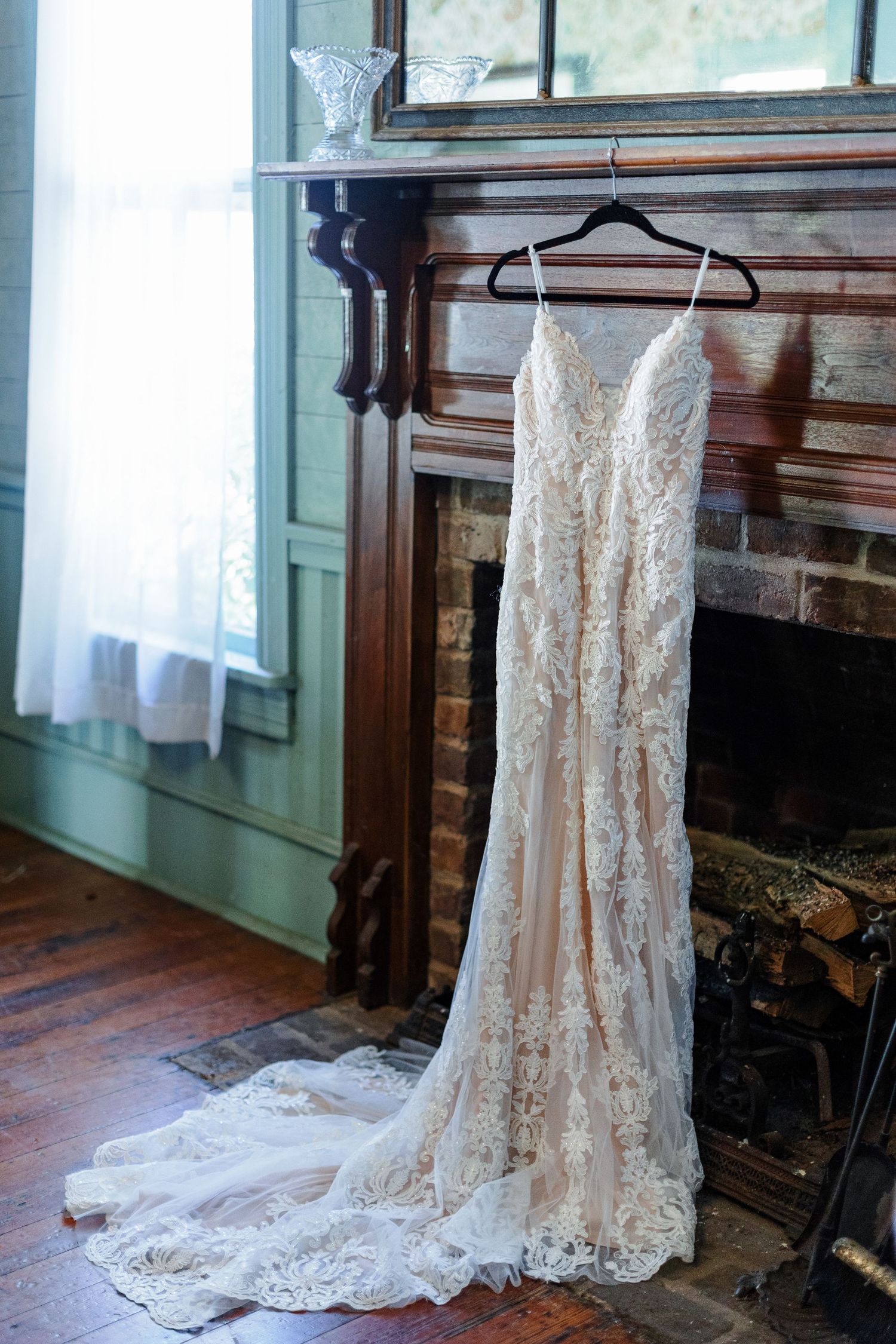 A wedding gown displayed in a colonial era parlor by a fireplace. Image by Emily Joy, wedding photographer in Memphis.