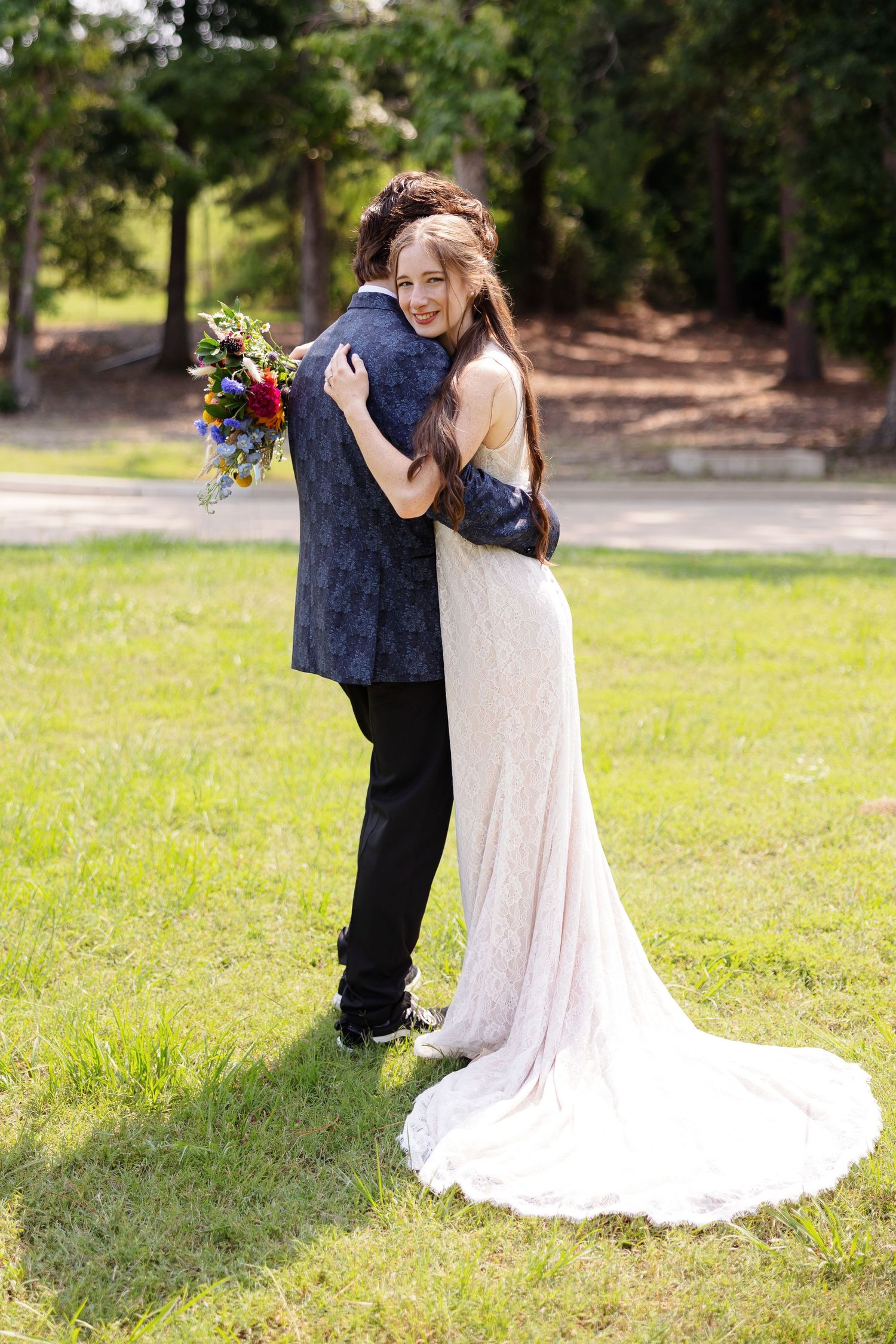 Bride and groom hug while bride smiles at camera for a portrait by Memphis wedding photographer Emily Joy Photography