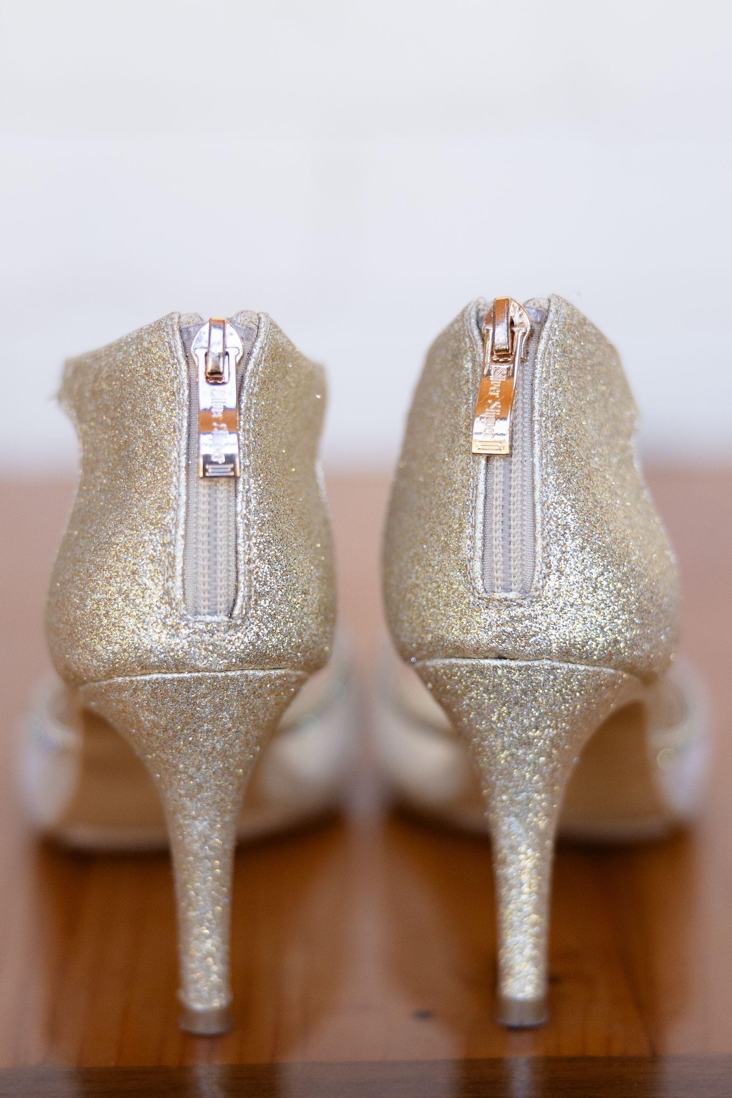 A glittery pair of golden high heels on a simple wooden platform. Image by Emily Joy, wedding photographer in Memphis.