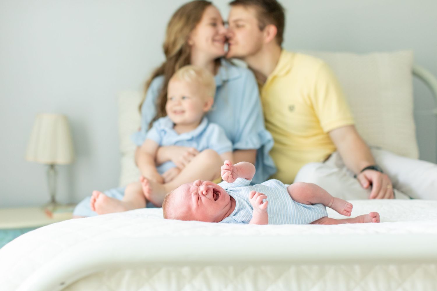 A newborn squeals as brother and parents snuggle for a portrait by Emily Joy Photography, now a wedding photographer in Memphis, TN.