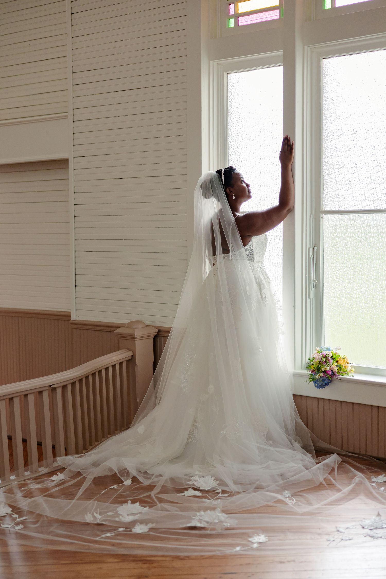 Elegant bride poses beside window with a serene expression for a portrait by Memphis Wedding Photographer Emily Joy Photography