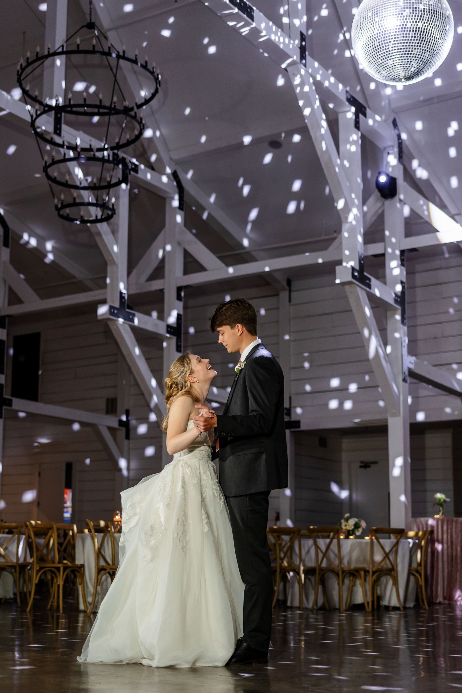 A bride and groom dance their last dance and smile at each other under disco lights. Image by Emily Joy, wedding photographer in Memphis.