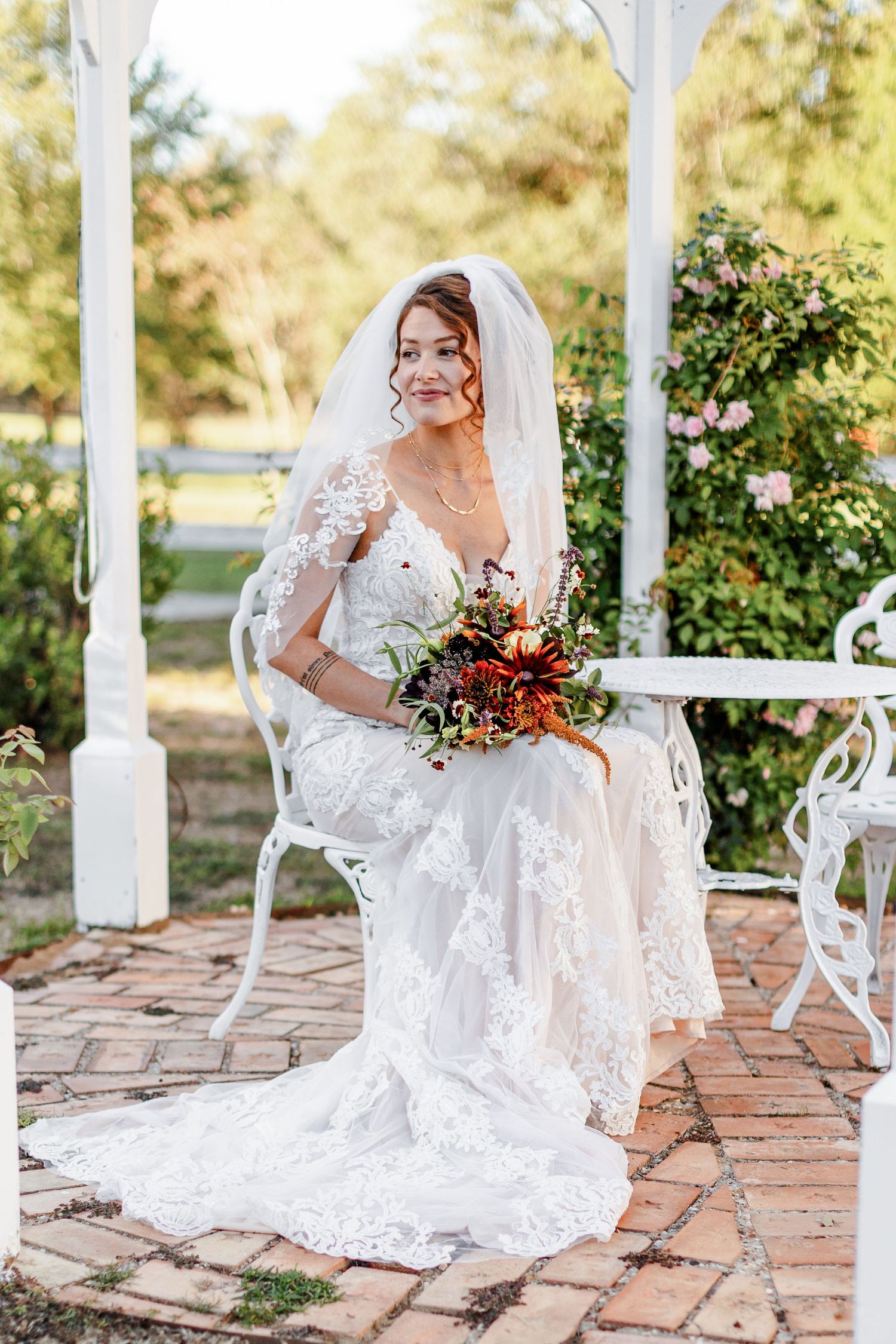 A bride, fully adorned and holding a bouquet, pictured in a white gazebo. Image by Emily Joy, wedding photographer in Memphis.