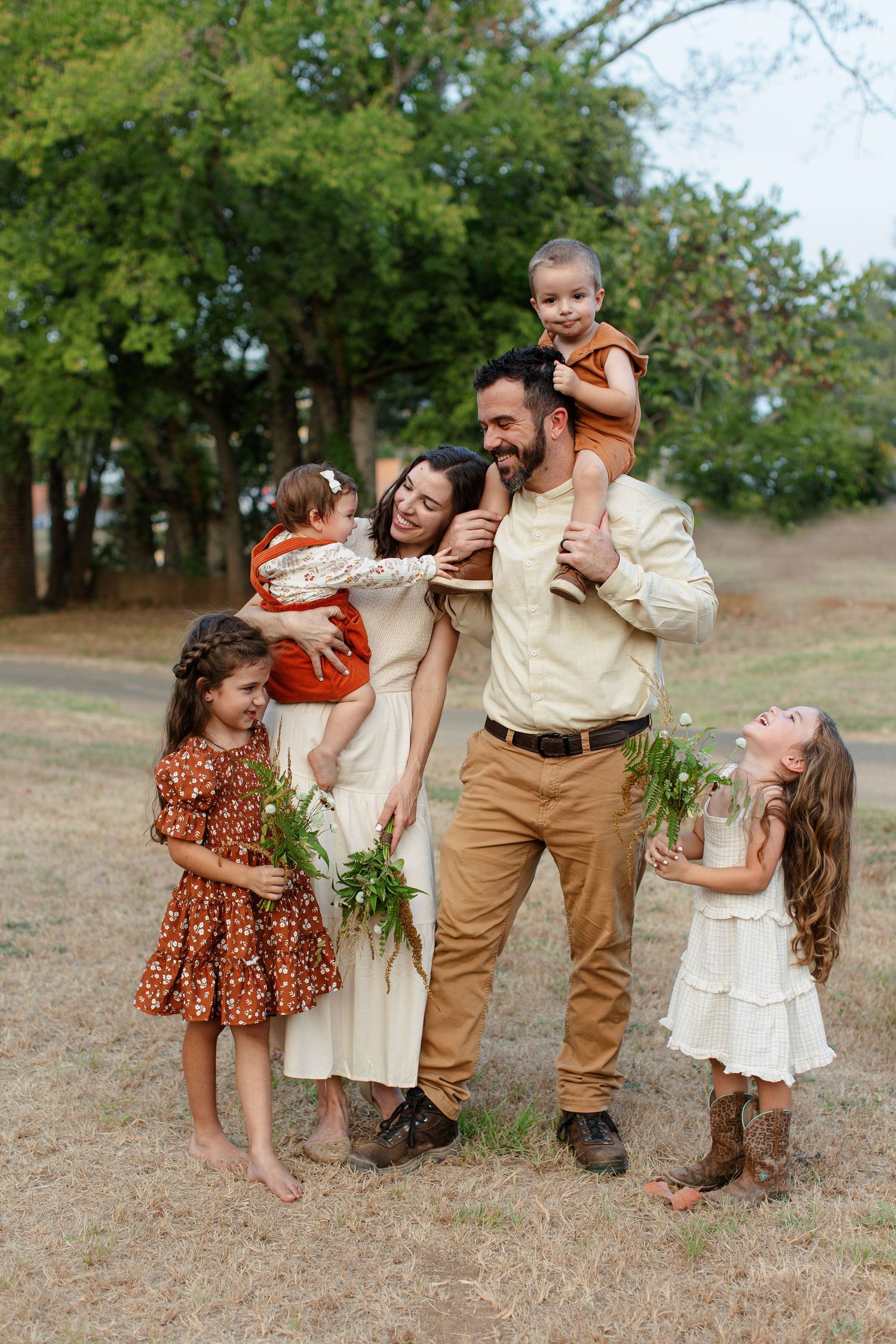 A young family with four children smile at each other for a portrait  by Emily Joy Photography, now a wedding photographer in Memphis, TN.