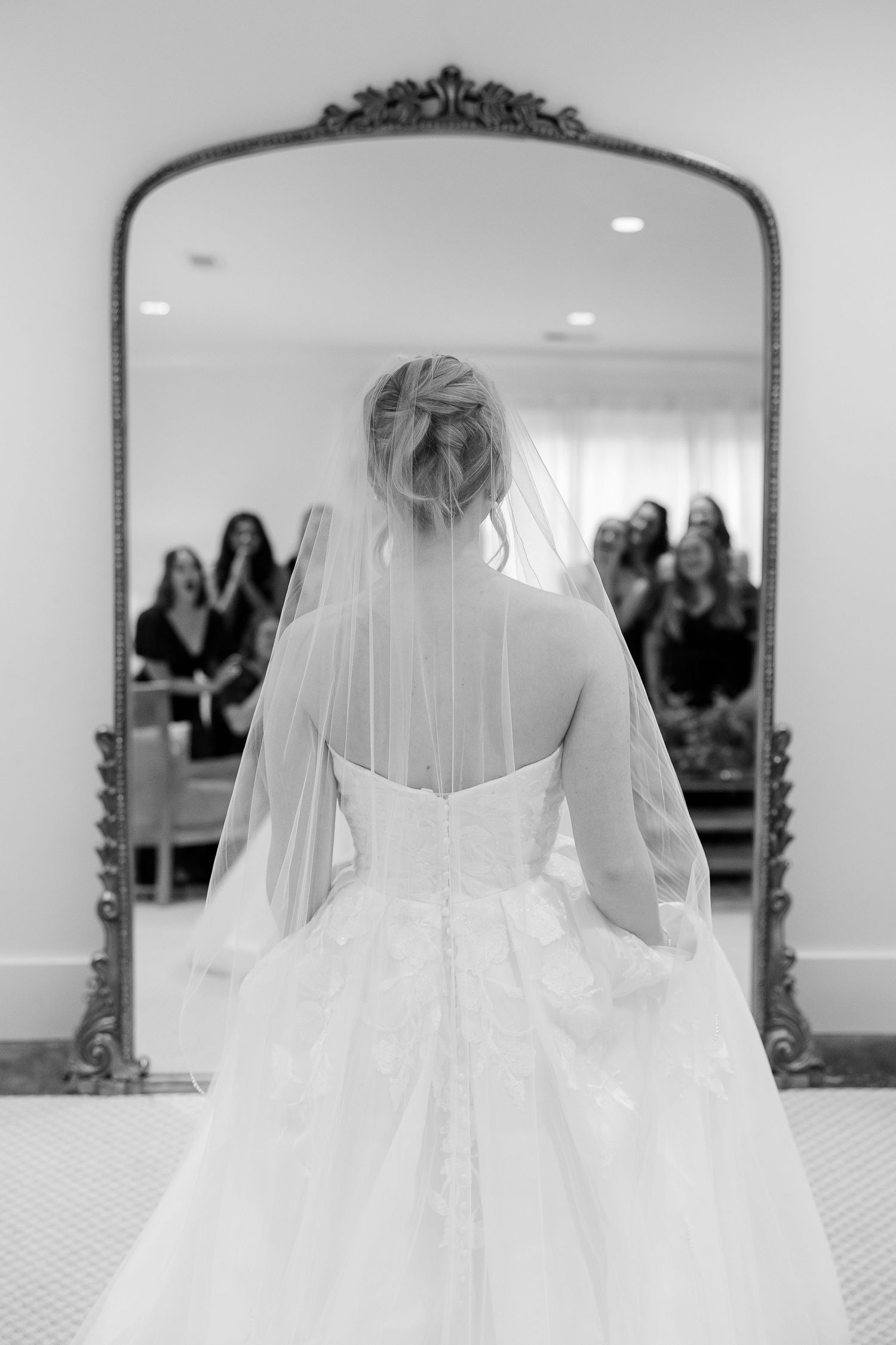An artistic through-the-mirror shot of bridesmaids admiring a bride's reflection by Memphis wedding photographer, Emily Joy Photography.