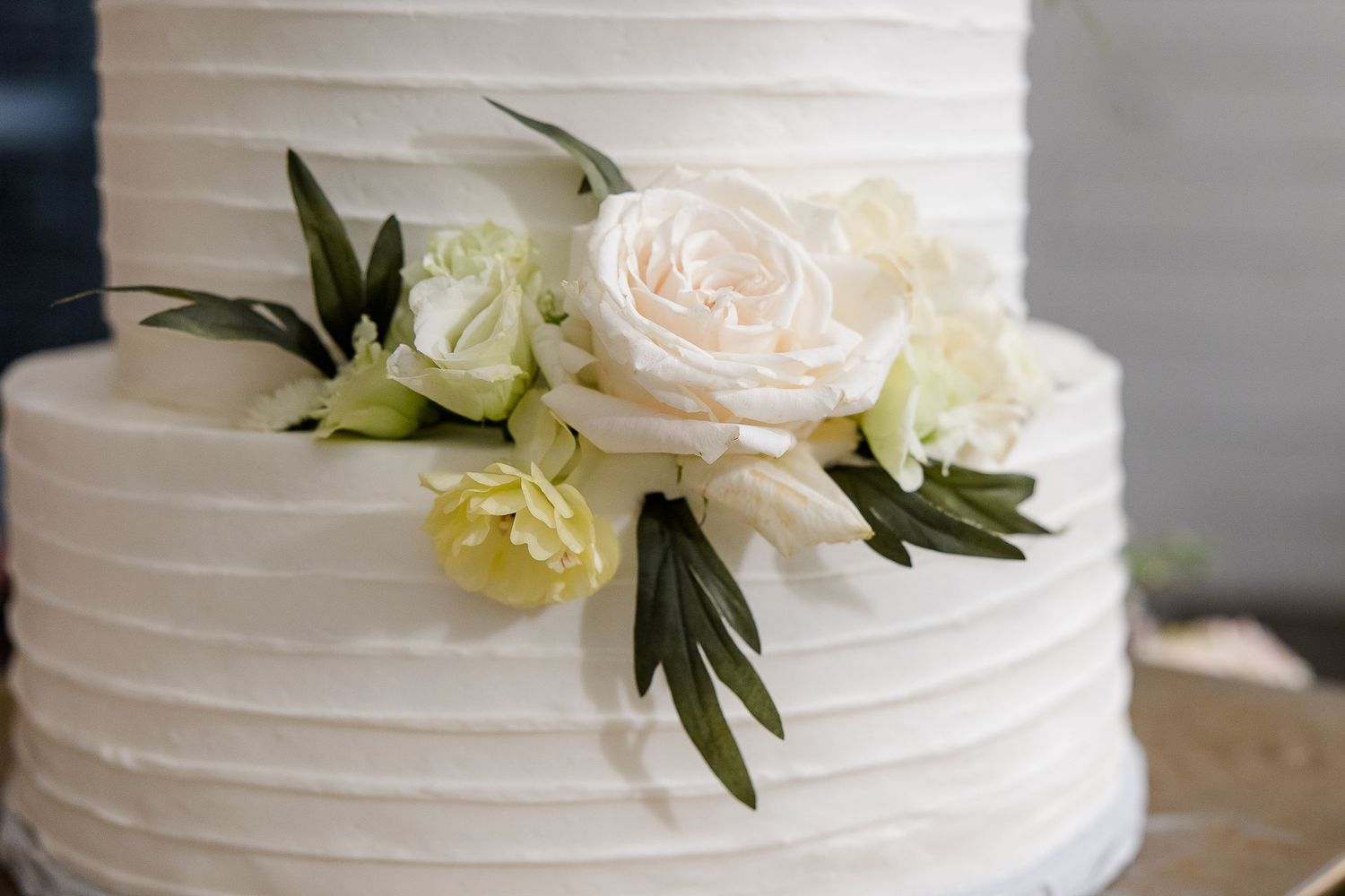 A close up shot of rose florals on a white frosted wedding cake, portrait by Memphis wedding photographer, Emily Joy Photography.
