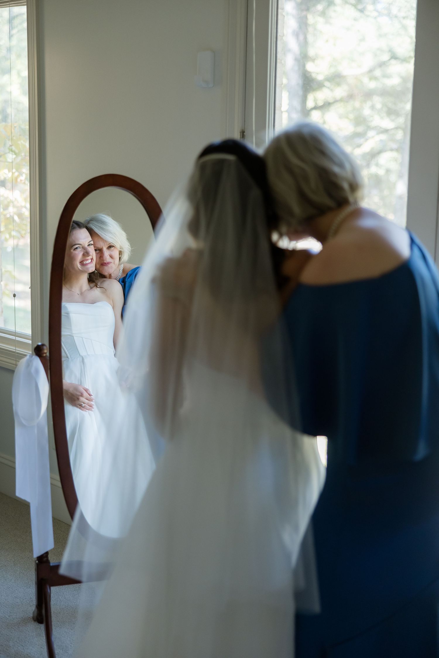 A mother admires her daughter, the bride, through a mirror for a portrait by Emily Joy Photography, wedding photographer in Memphis, TN.
