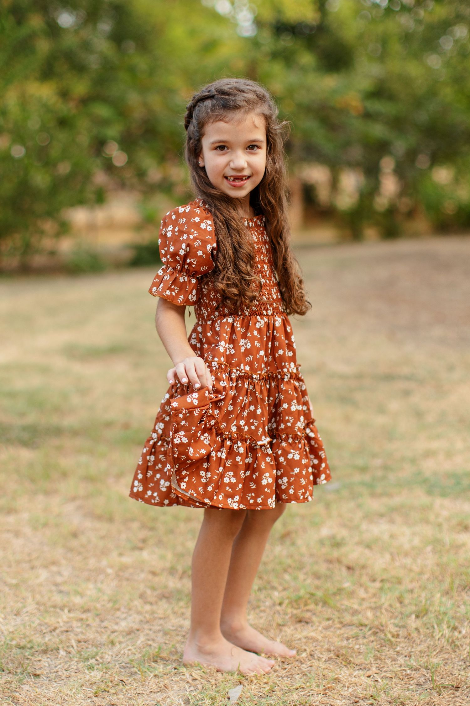 A little girl barefoot in a field of grass for a portrait  by Emily Joy Photography, now a wedding photographer in Memphis, TN.