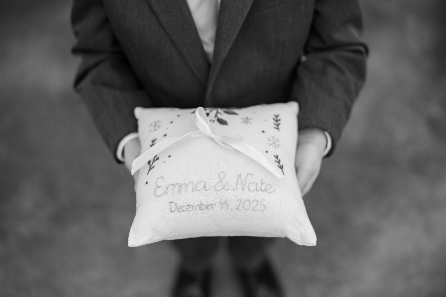 A young ringbearer holds a pillow personalized for the bride and groom.