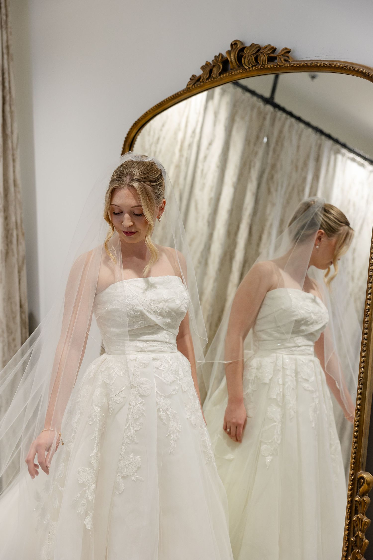 A bride and her reflection as she adjusts her veil. Image by Emily Joy, wedding photographer in Memphis.