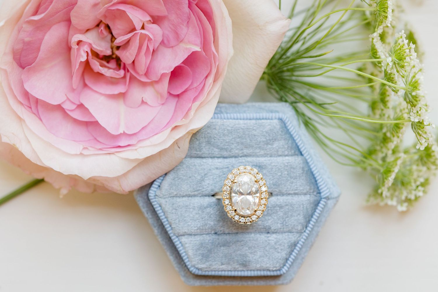 An engagement ring in a blue velvet ring box, framed by green and pink florals, by Memphis wedding photographer, Emily Joy Photography.