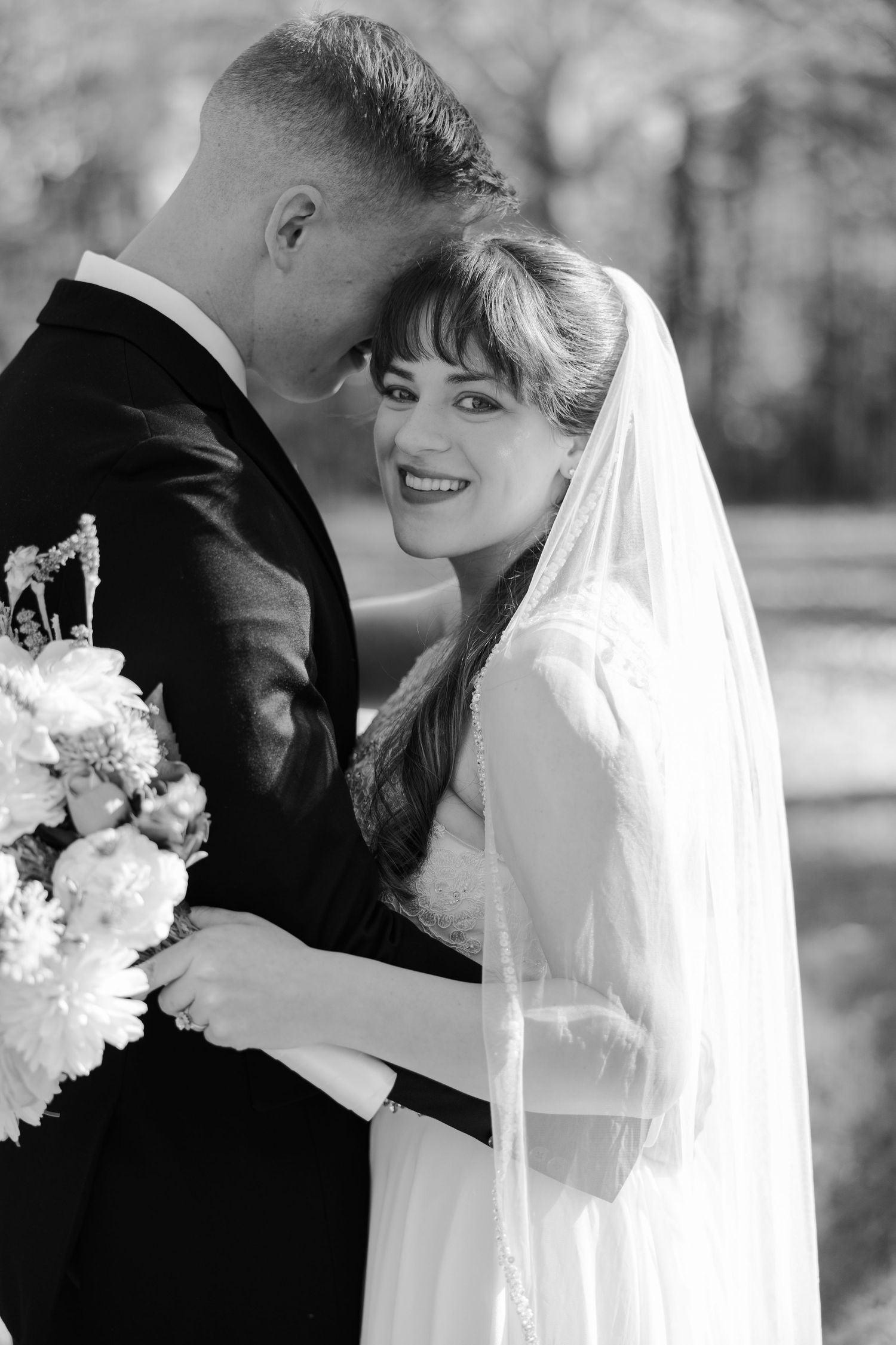 A groom nuzzles his bride while she smiles joyfully at the camera. Image by Emily Joy, wedding photographer in Memphis.