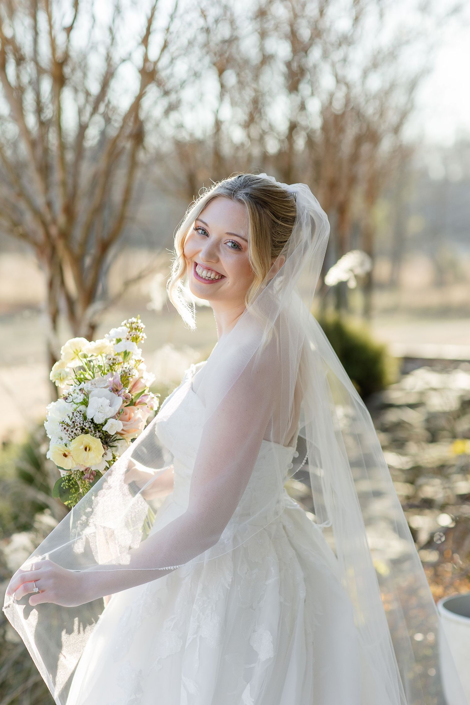 A cheerful bride turns around to smile at the camera on a bright, sunny day; portrait by Memphis wedding photographer, Emily Joy Photography