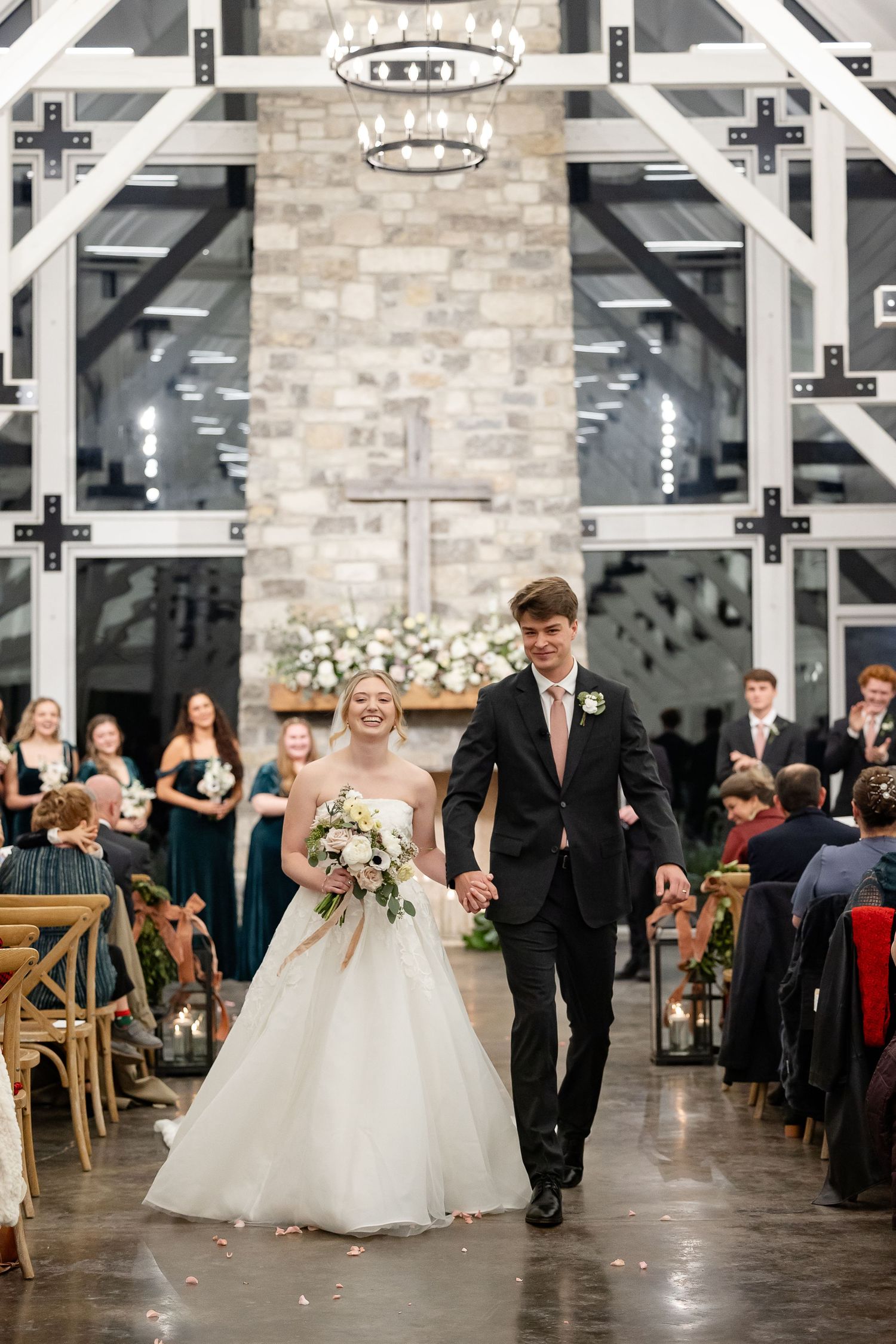 A joyful bride and groom recess after ceremony, smiling and holding hands. Image by Emily Joy, wedding photographer in Memphis.