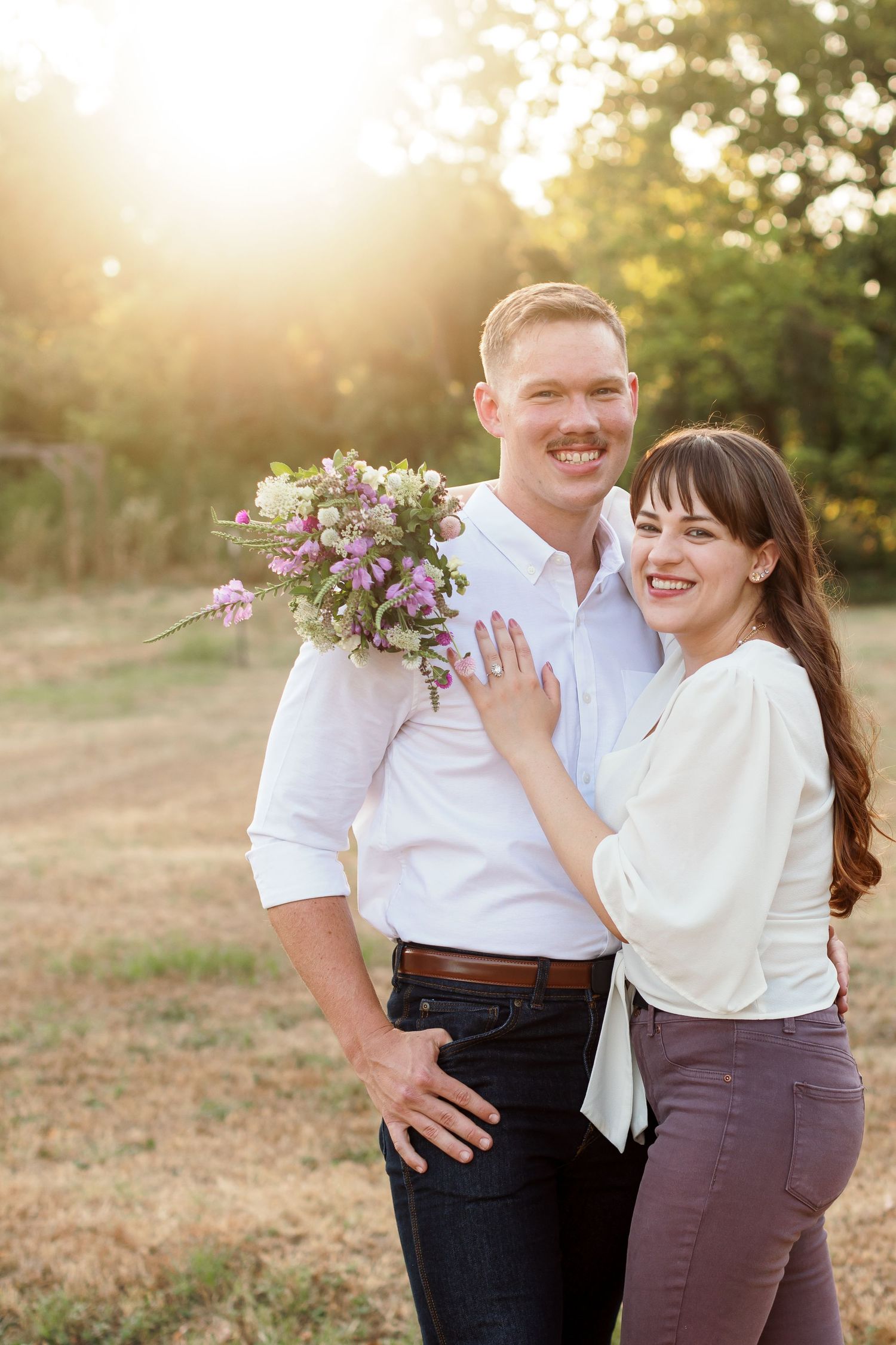 An engaged couple smiles at the camera for a portrait by Emily Joy Photography, now a wedding photographer in Memphis, TN.