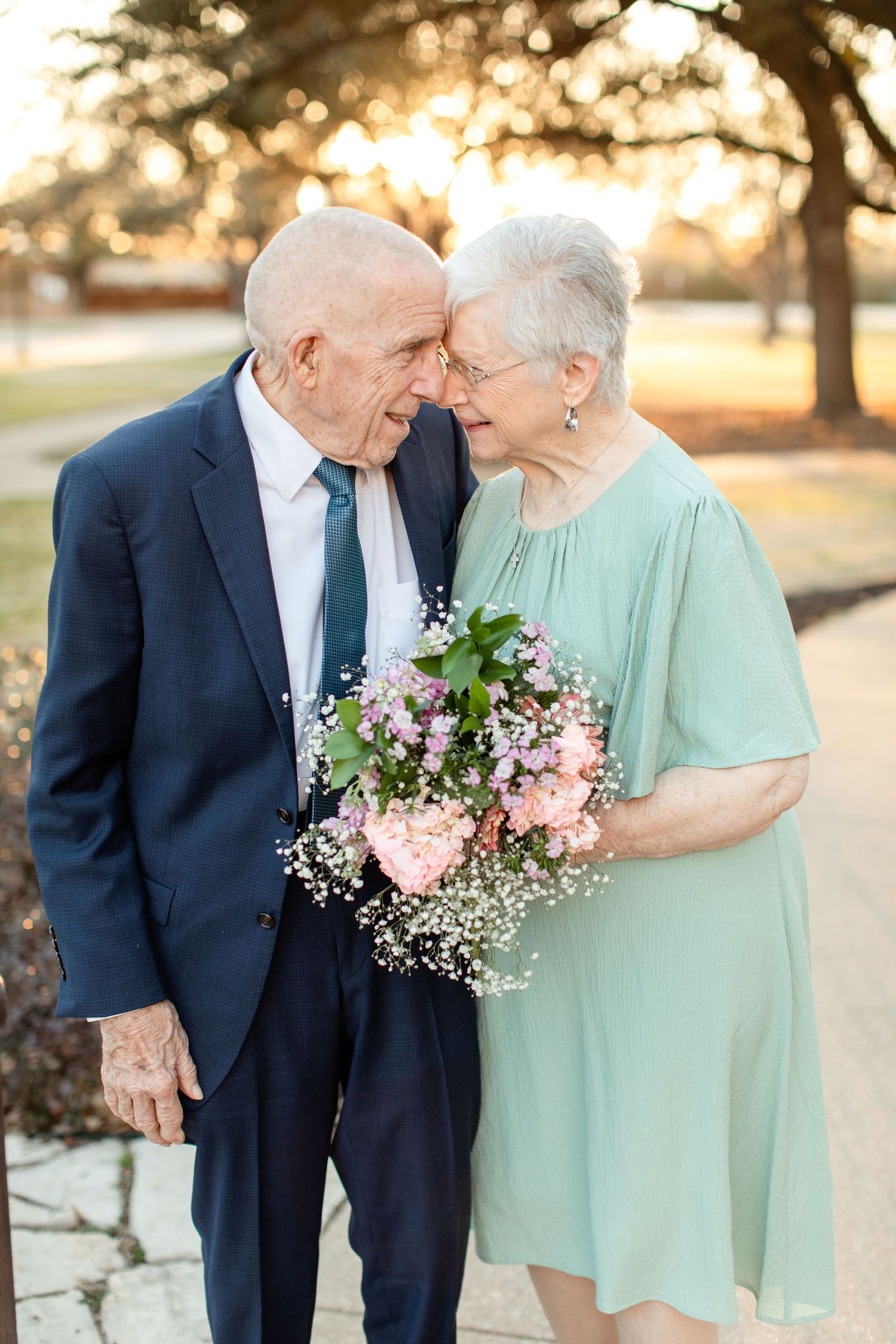 An elderly married couple, foreheads together, smiles for a portrait by Emily Joy Photography, now a wedding photographer in Memphis, TN.